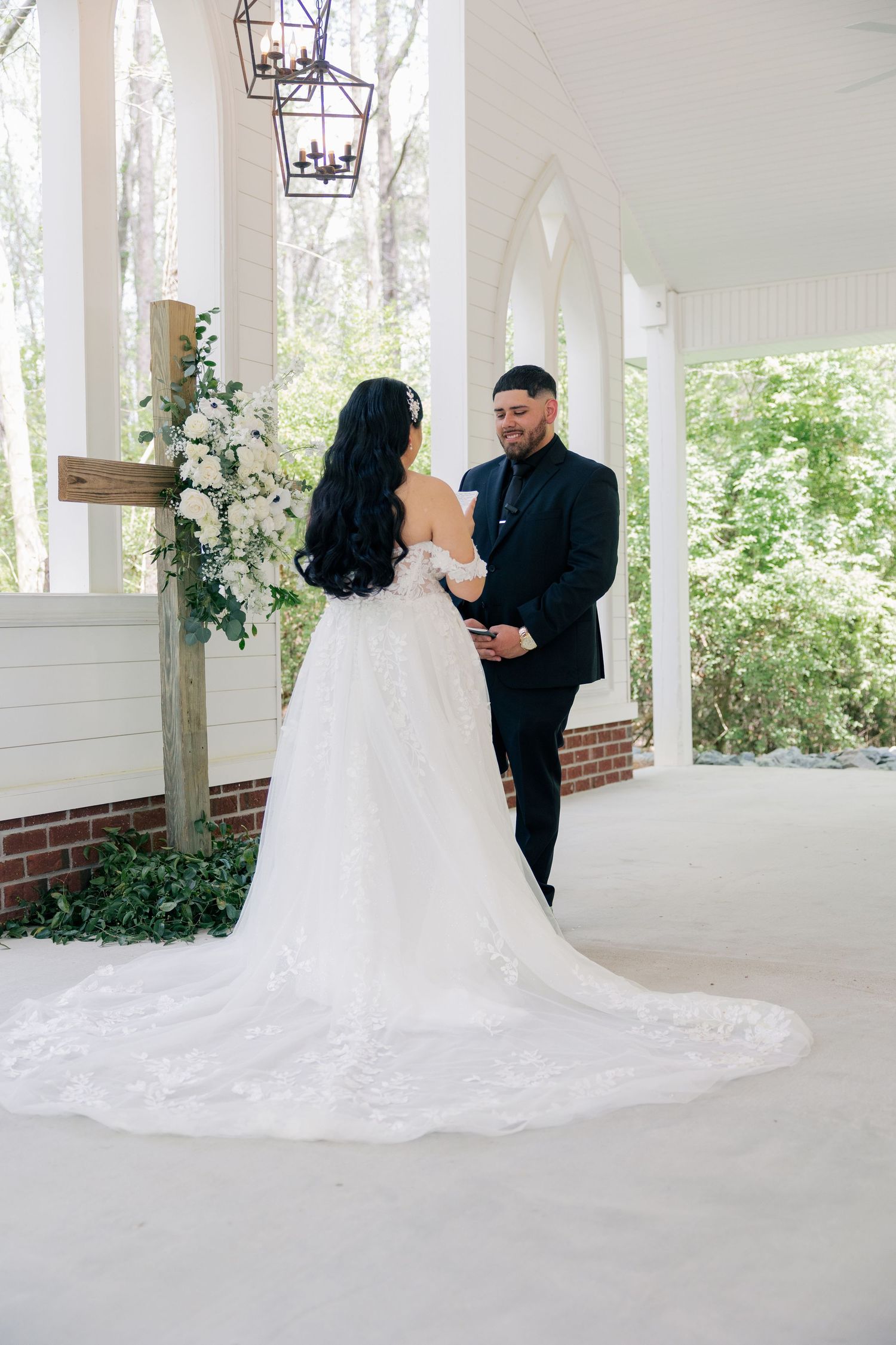 A bride and groom share their first look on an elegant white columned porch.