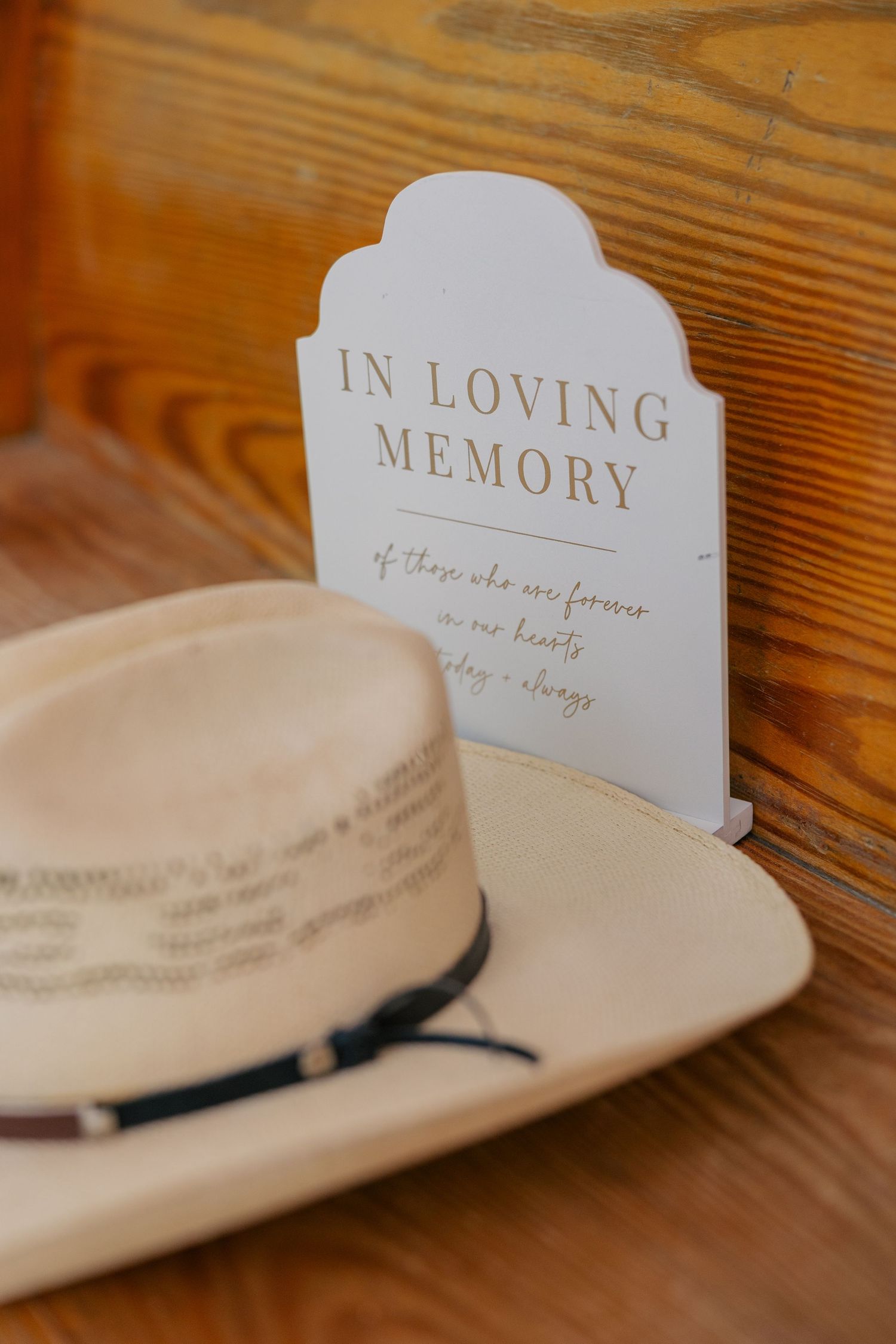Memorial cards and a cowboy hat sit on a wooden surface in a rustic setting.