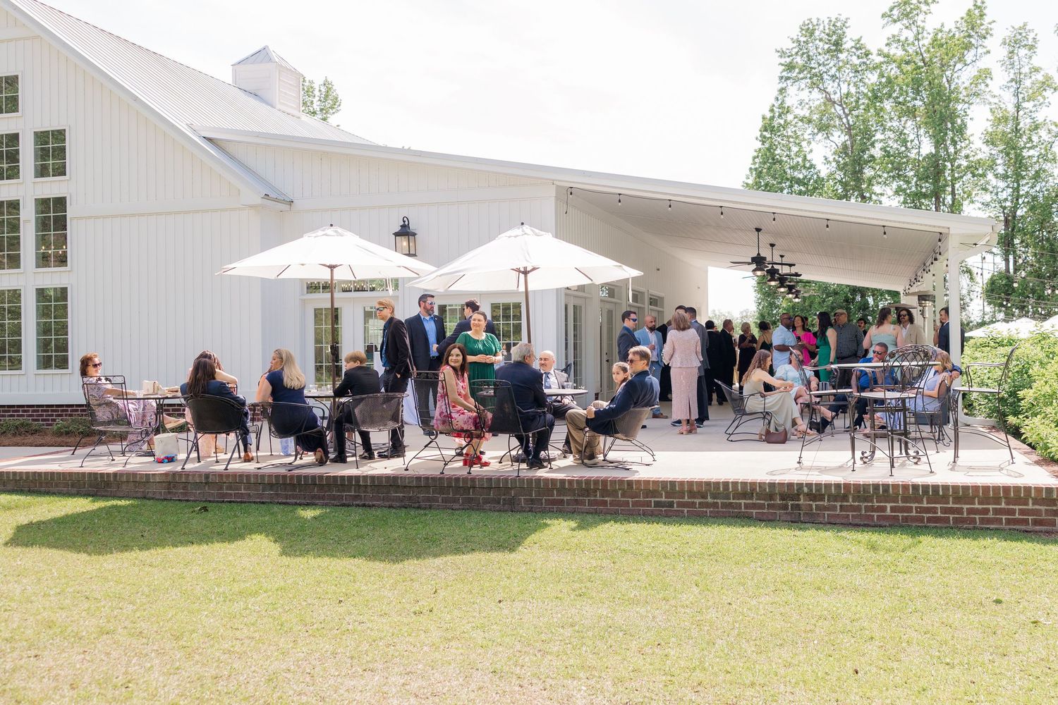 Panoramic view of a white wedding venue with outdoor reception setup and umbrellas.