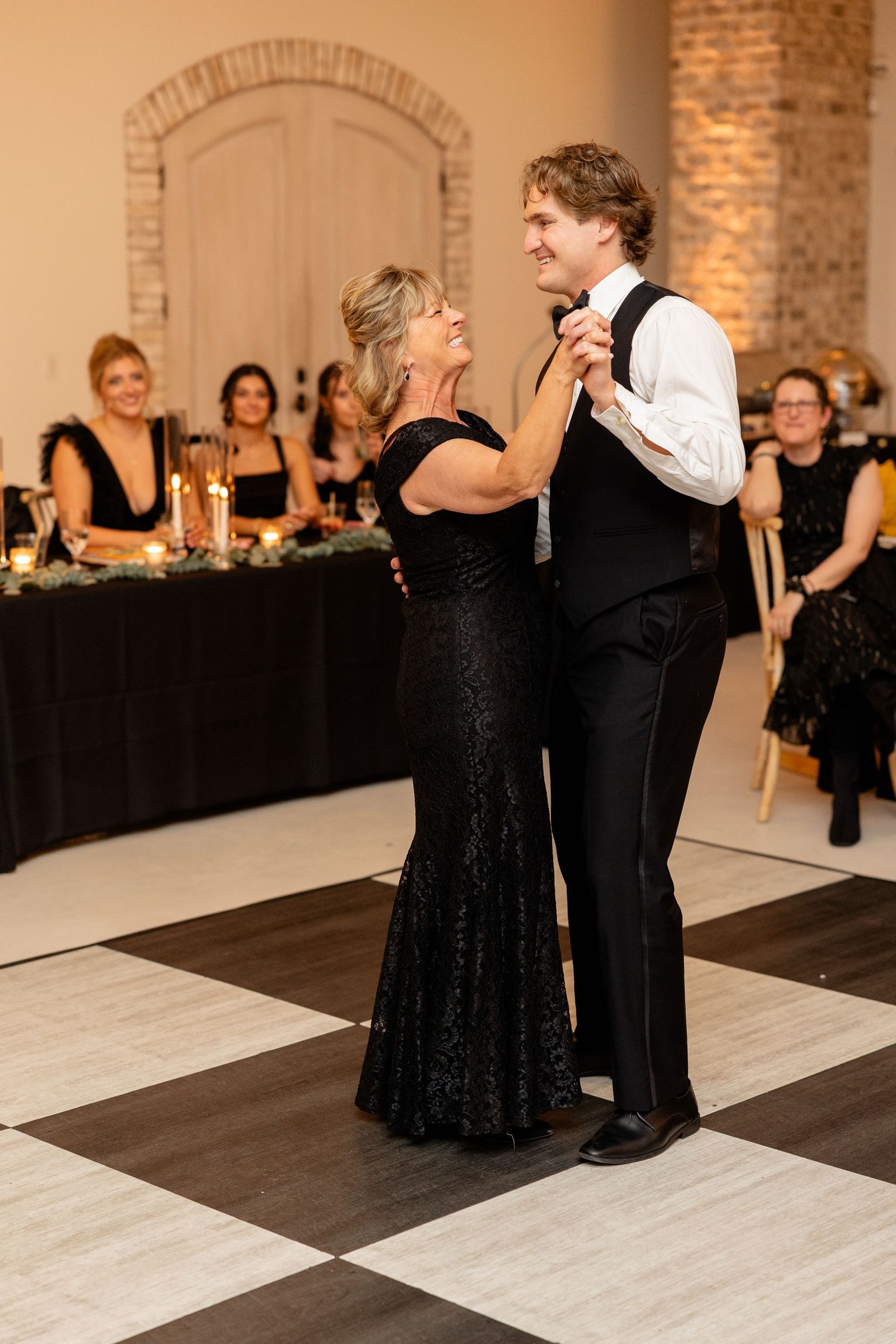An intimate dance moment during a wedding reception in an elegant venue with brick walls.
