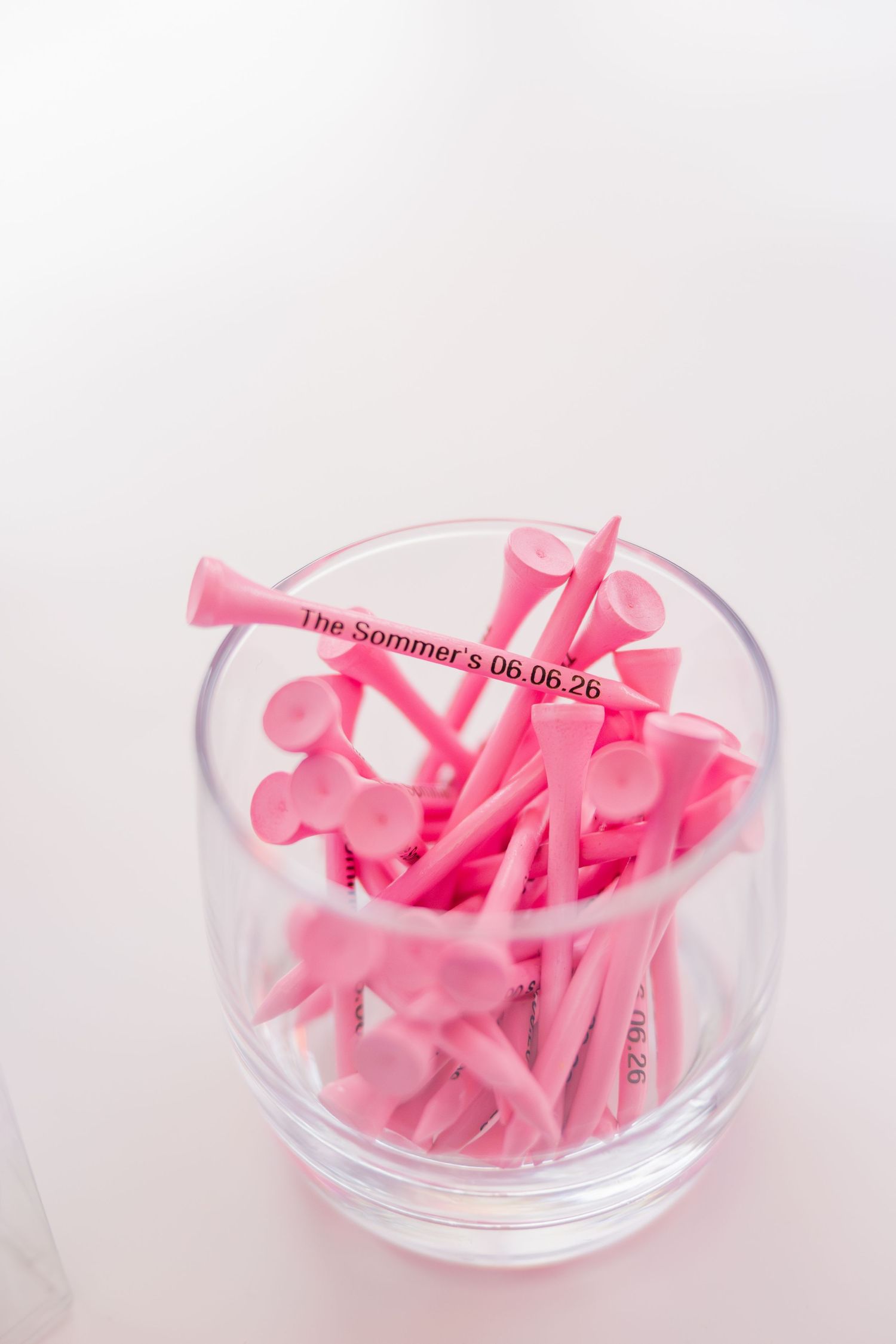 Personalized pink golf tees in glass reading The Sommers 06.06.26 as wedding favor detail.