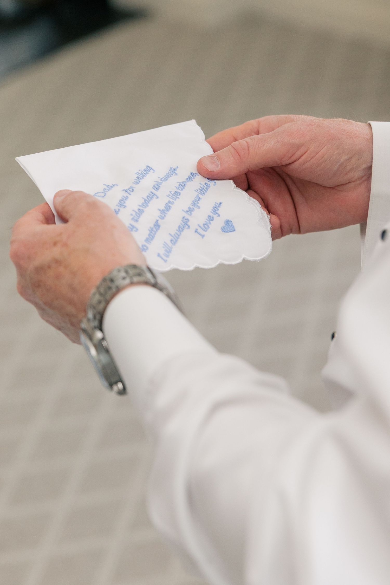 Groom reads handwritten note from bride on wedding day holding scalloped card.