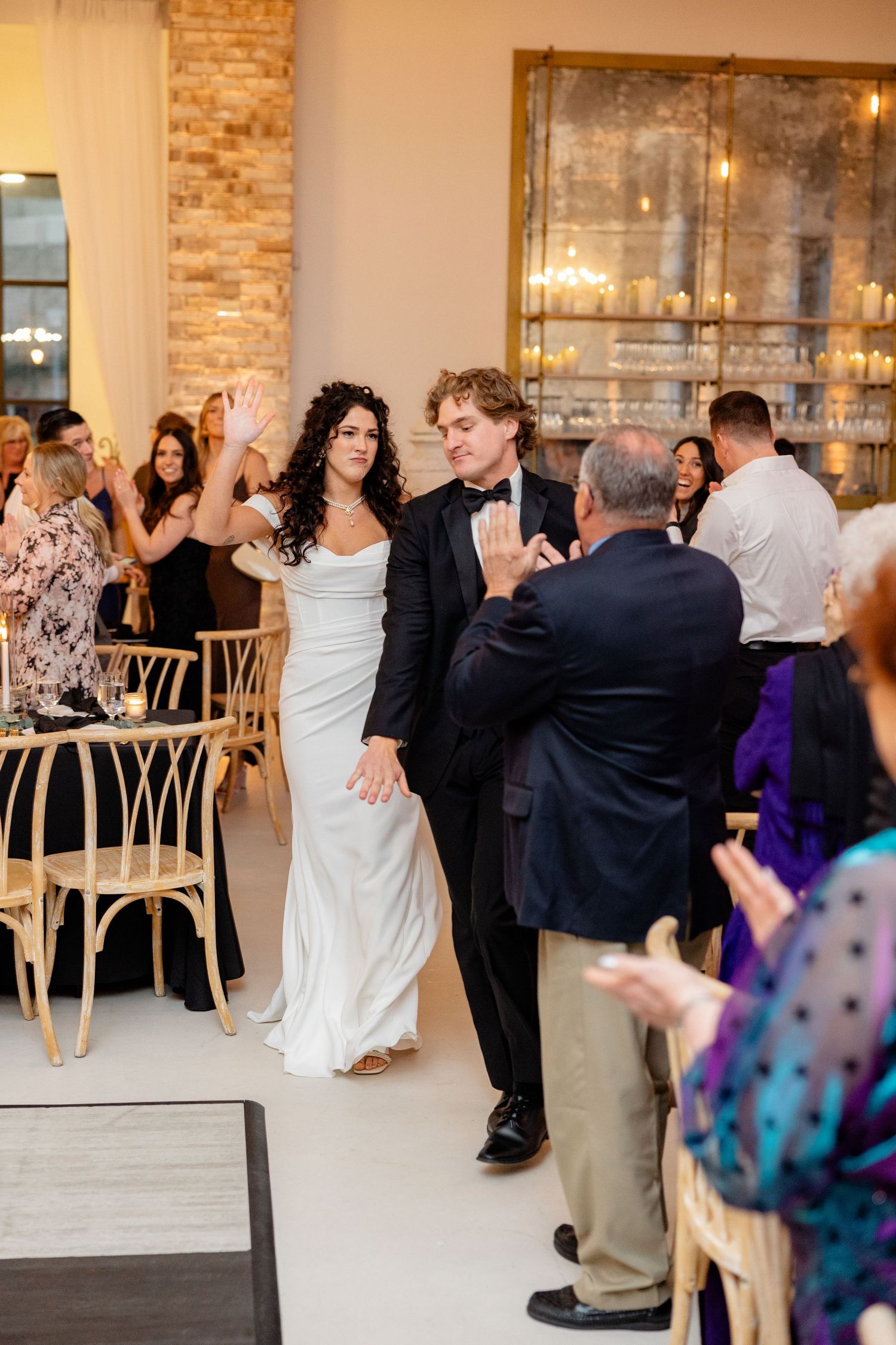A joyful celebration during a wedding reception in an elegant venue with exposed brick walls.