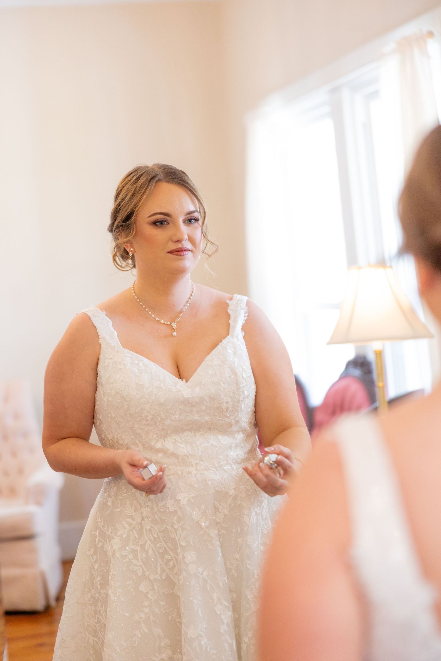 Beautiful wedding dress with lace details being prepared in a sunlit room.
