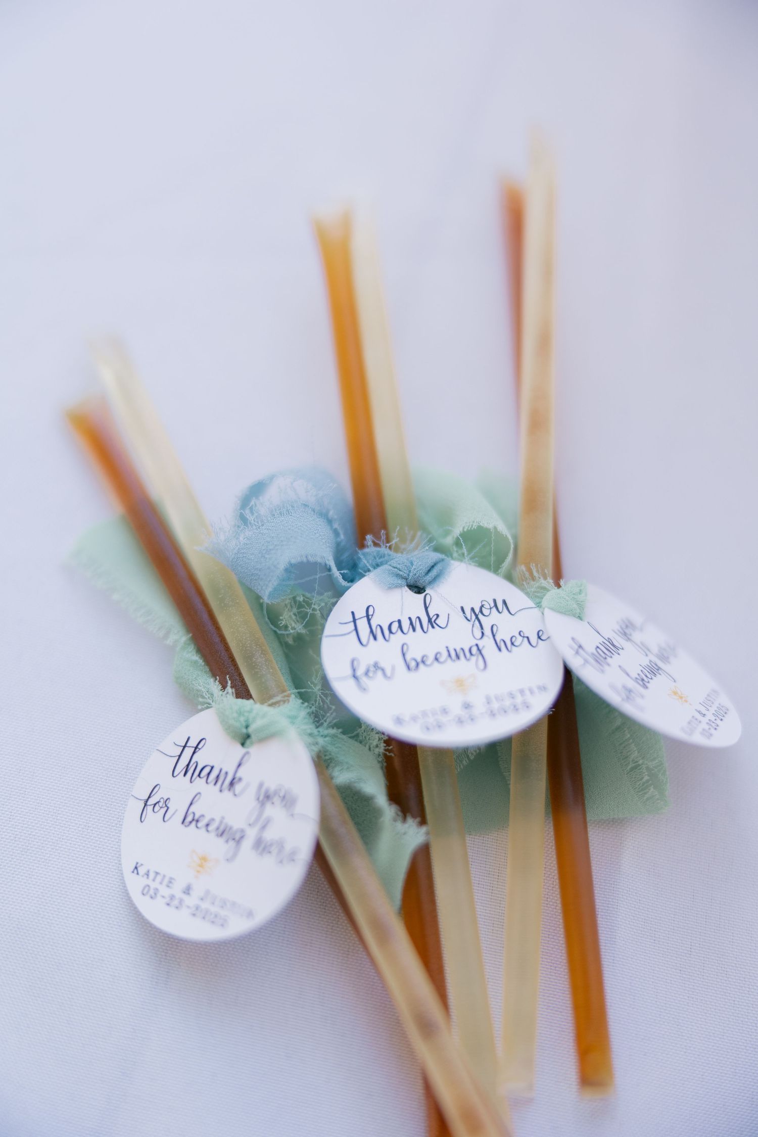 Close-up of honey dipper wedding favors with thank you tags and mint green ribbons.