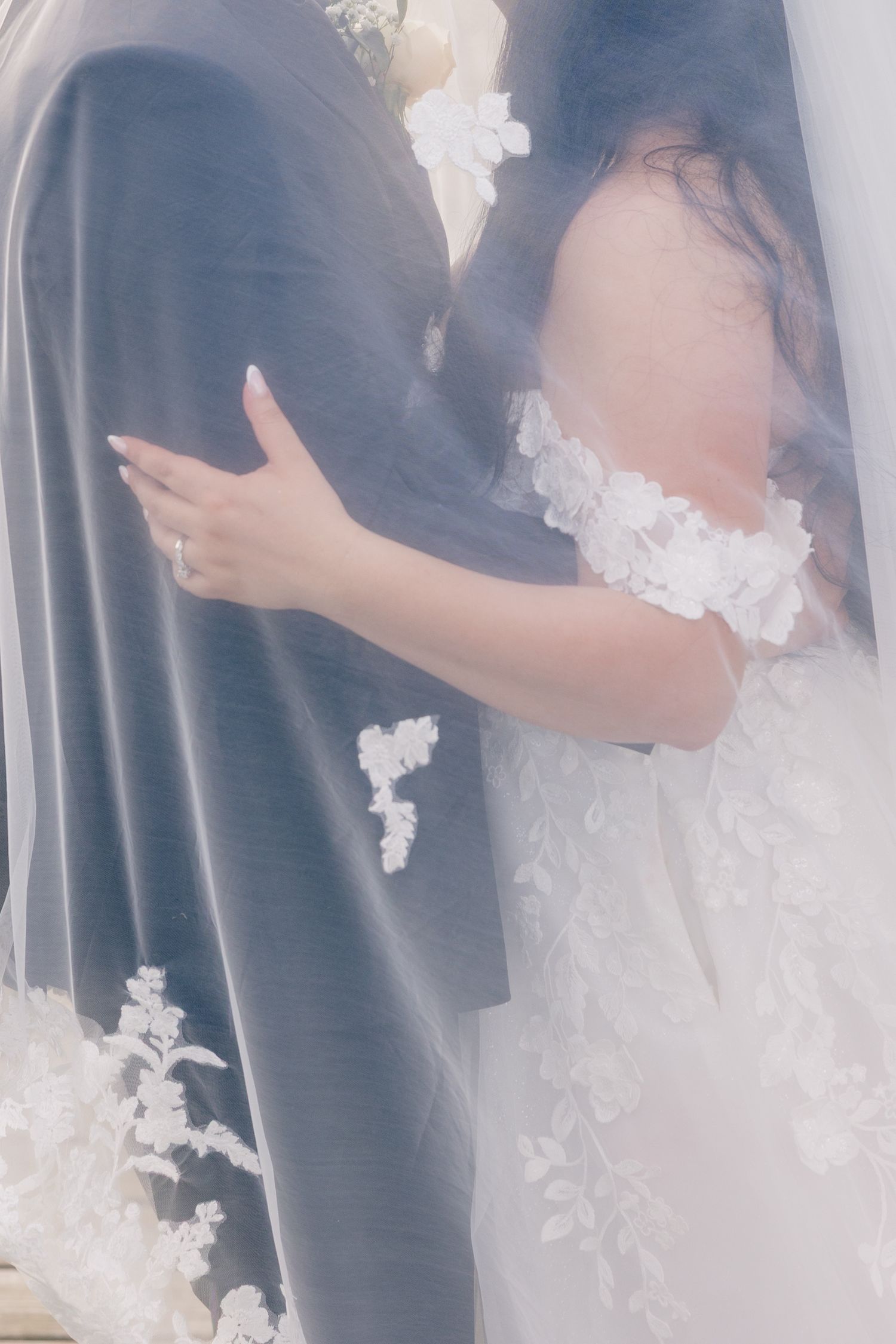 Close-up details of white lace appliques on a flowing wedding gown veil.