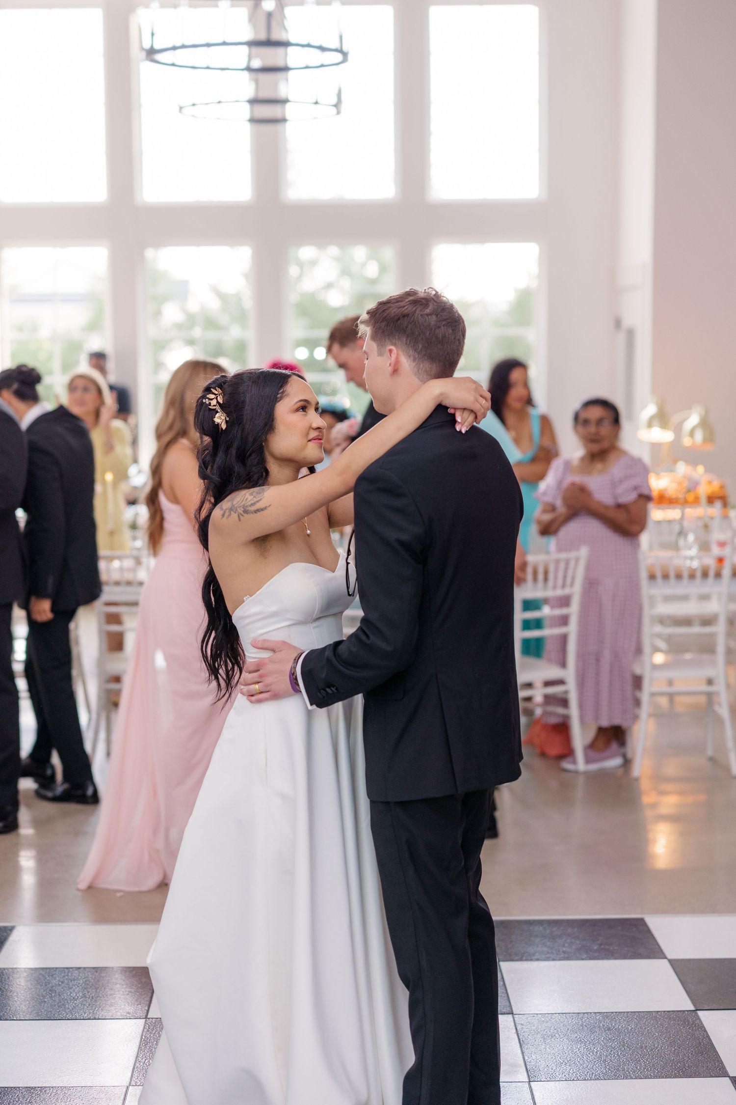 Couples slow dancing on checkered floor during elegant wedding reception.