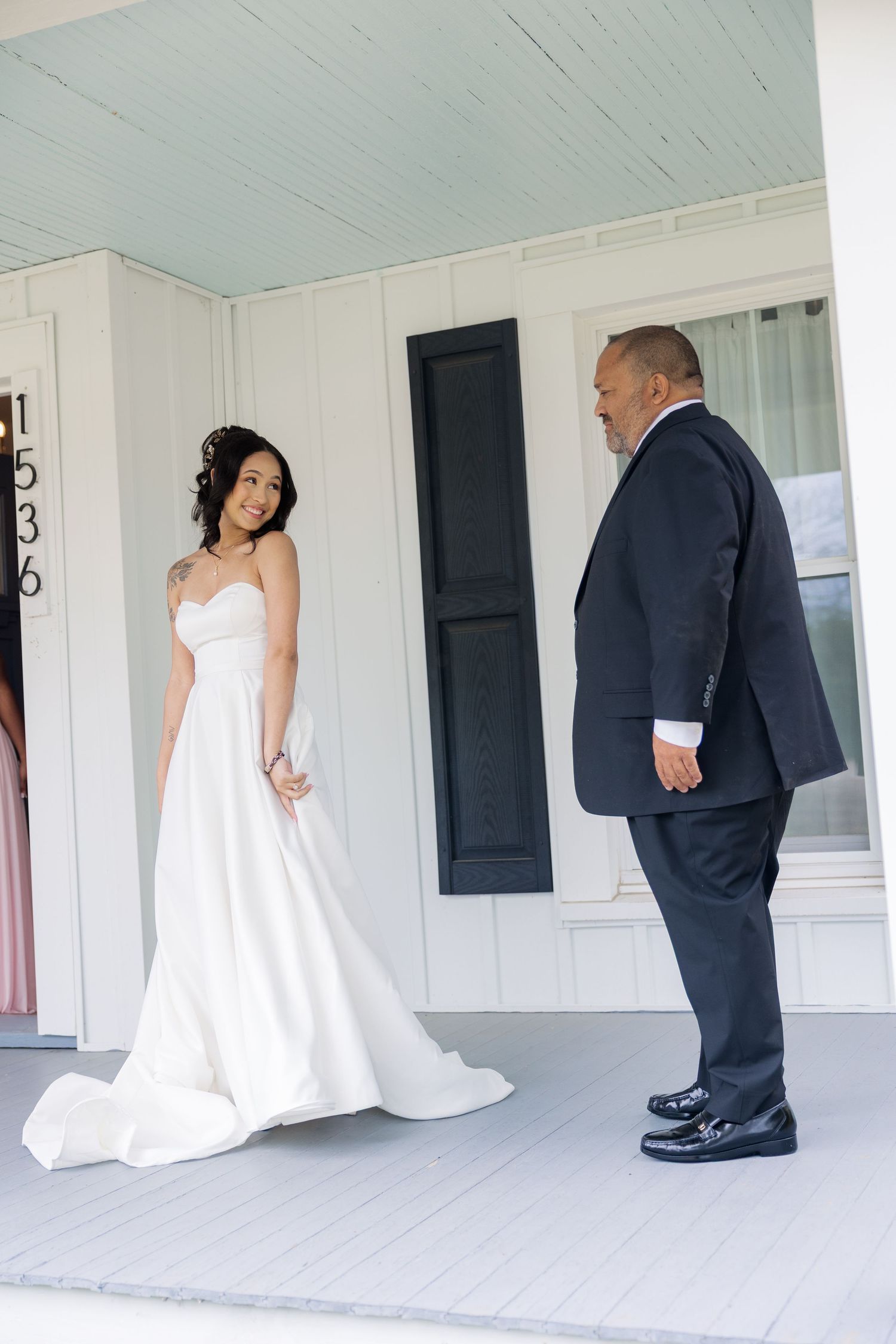 A special moment captured on a white porch between two people during a wedding celebration.