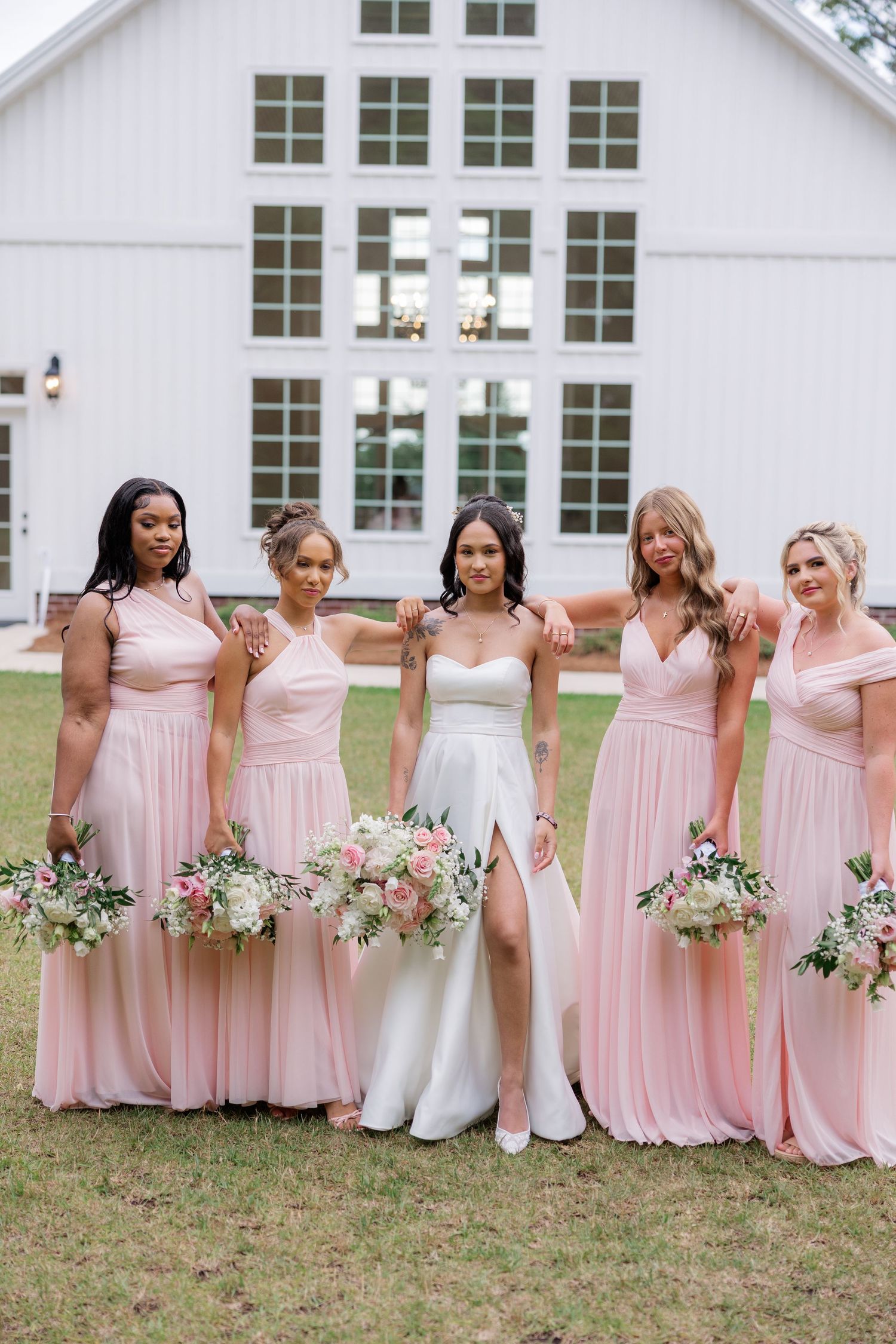 Wedding party poses playfully together wearing pink bridesmaid dresses and white bridal gown.