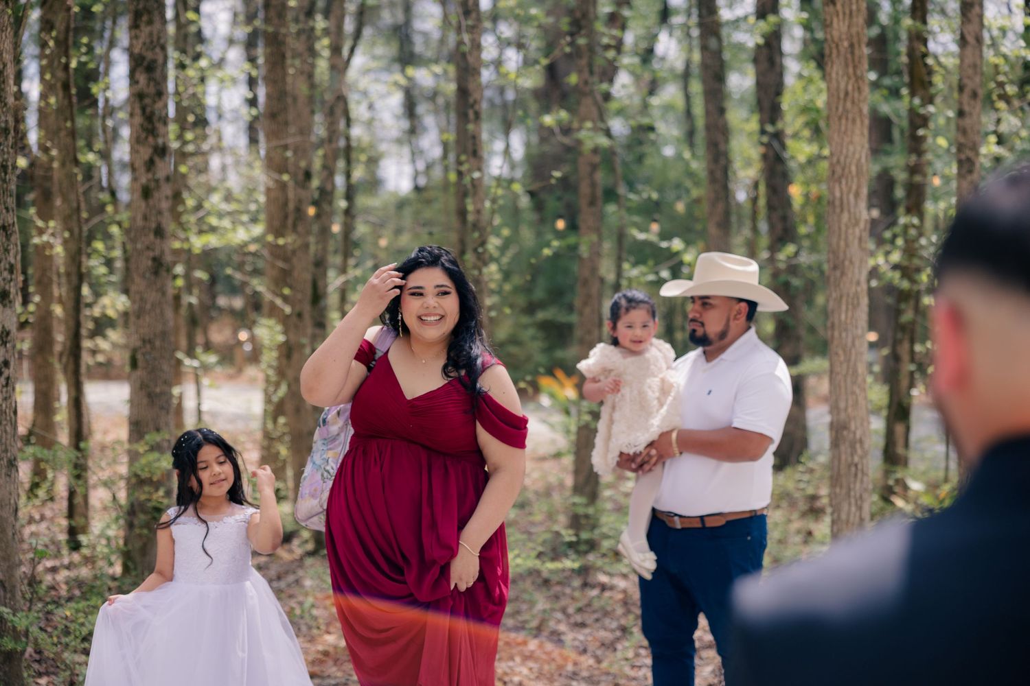 Wedding party celebrating outdoors in a wooded setting on a sunny day.