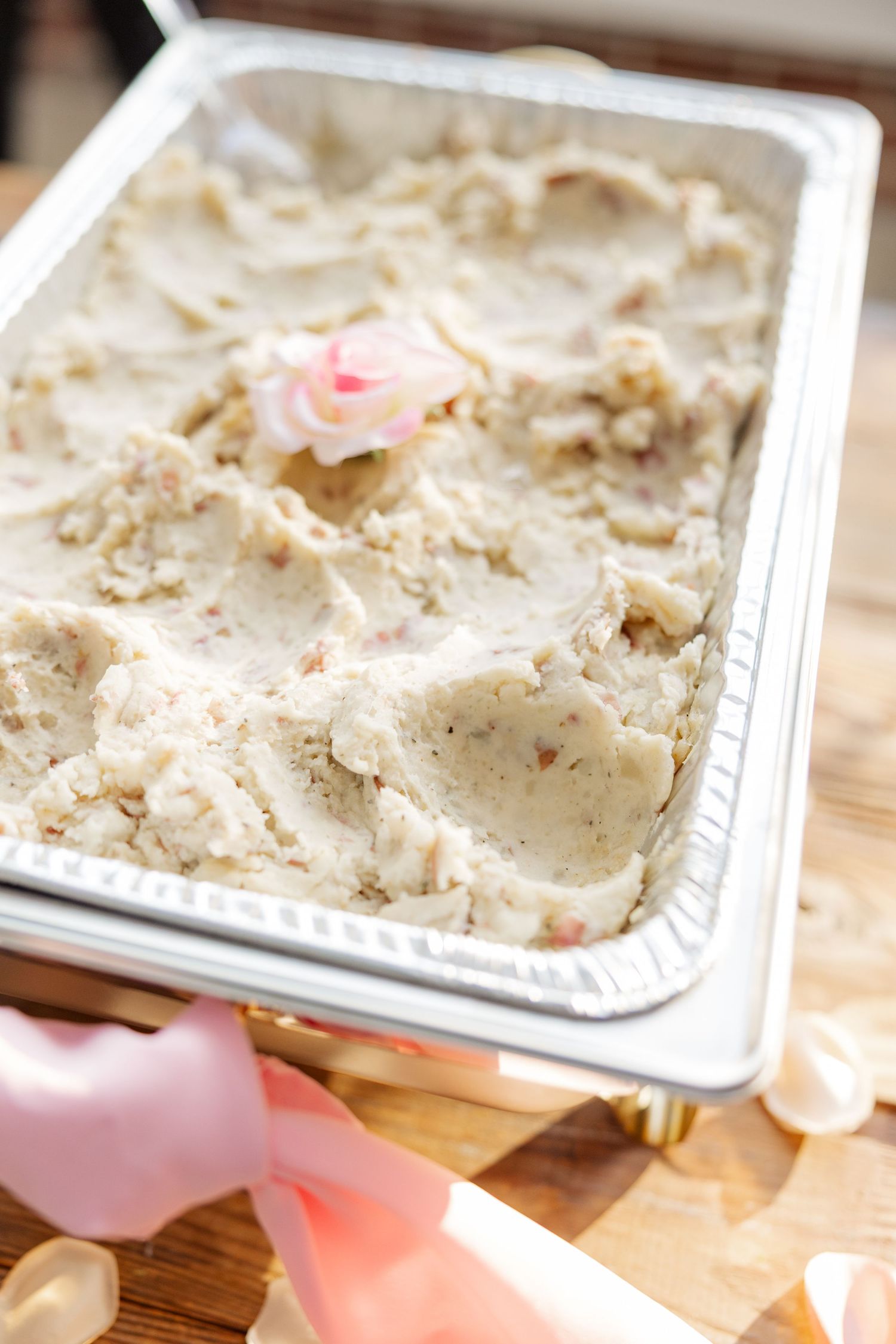 A pan of creamy dessert with pink accents and rose petals.