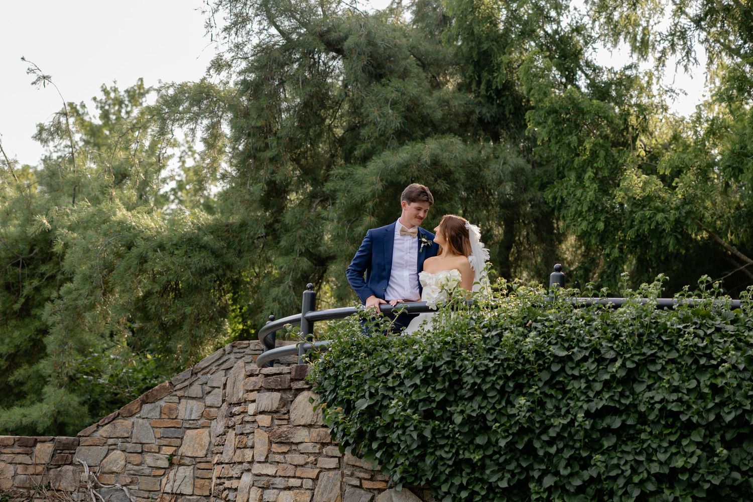 A romantic stone wall garden setting with lush greenery and natural lighting at dusk.