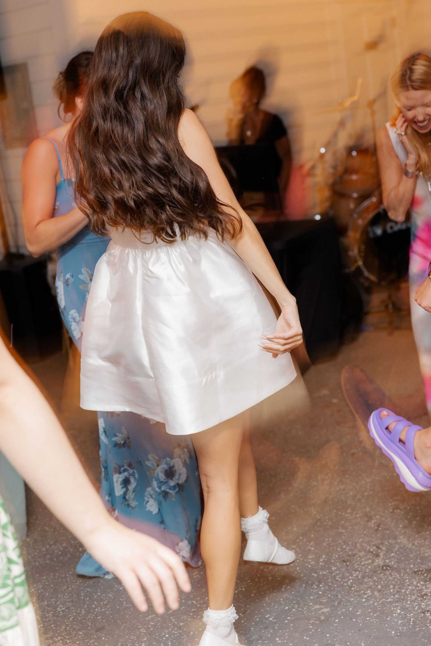 Wedding guests dancing and celebrating on a sparkly dance floor at an evening reception.