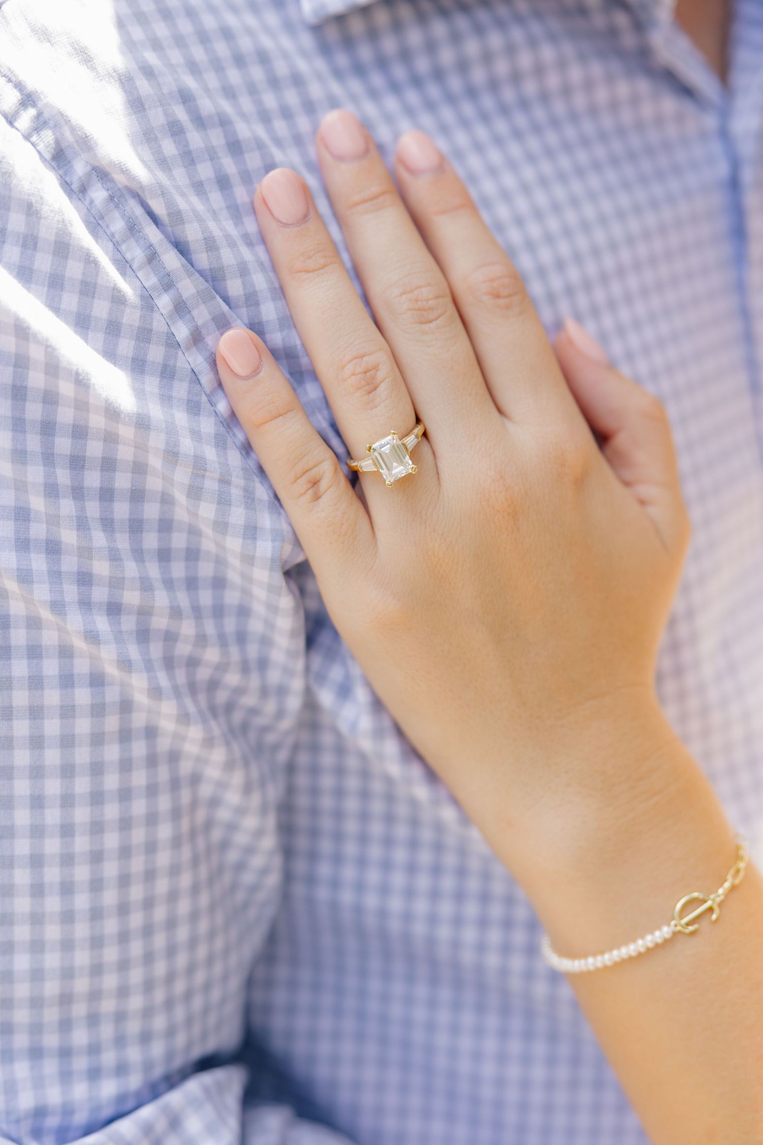 Close-up of engagement ring featuring large emerald cut diamond in gold setting on brides hand.