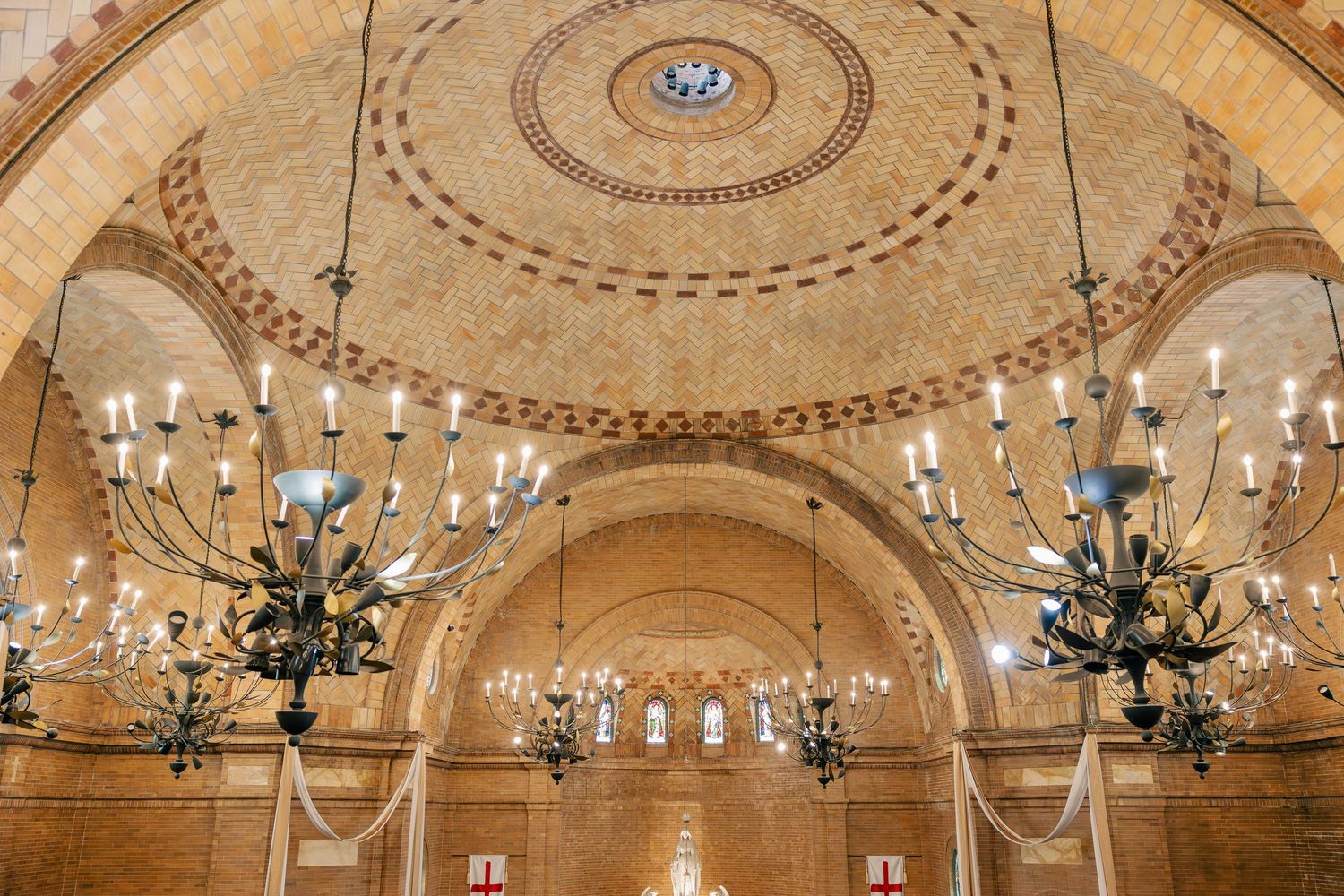 Grand domed ceiling with ornate chandeliers and arched windows inside a historic wedding venue.