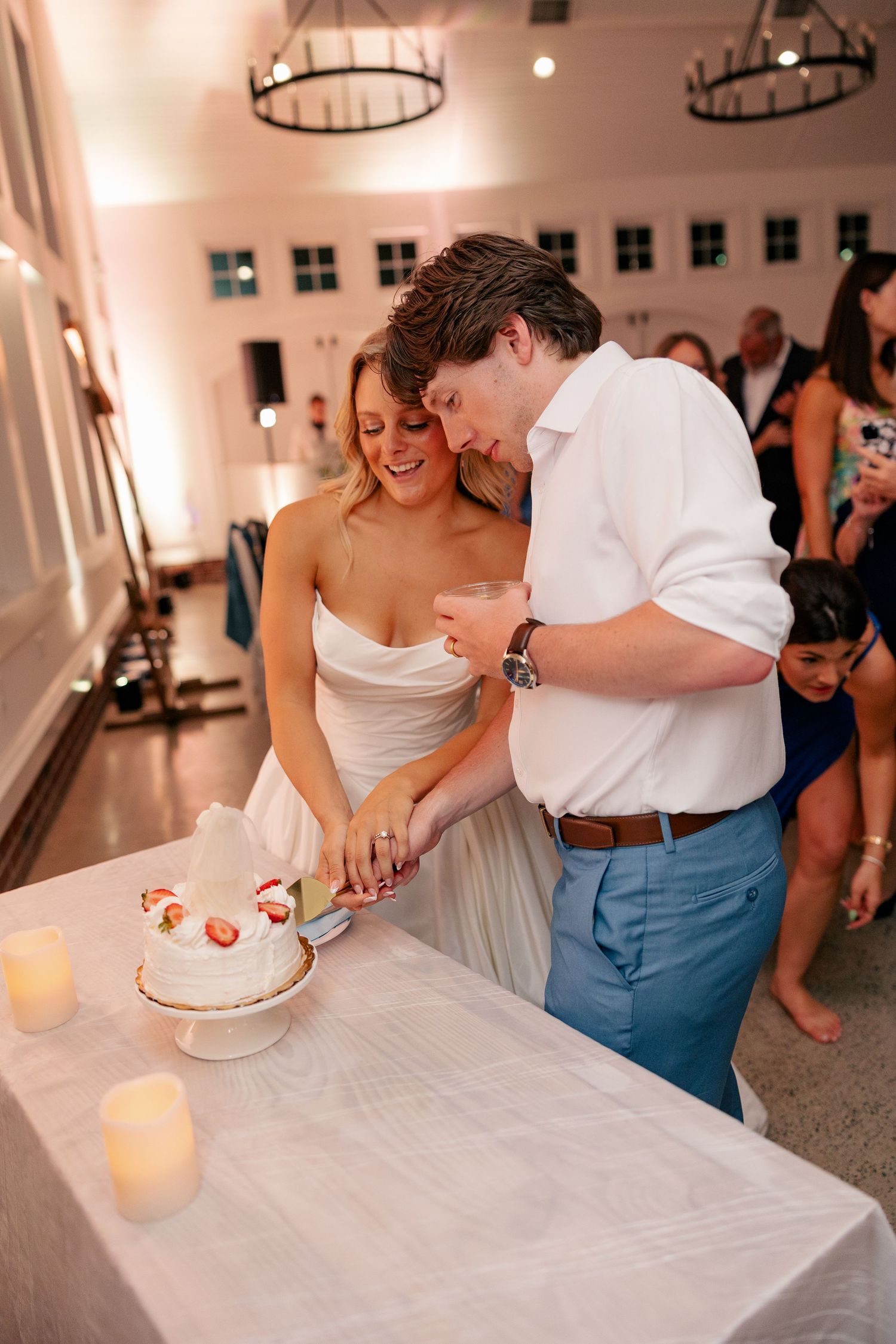 Bride and groom cutting their white wedding cake together at their elegant indoor wedding reception.
