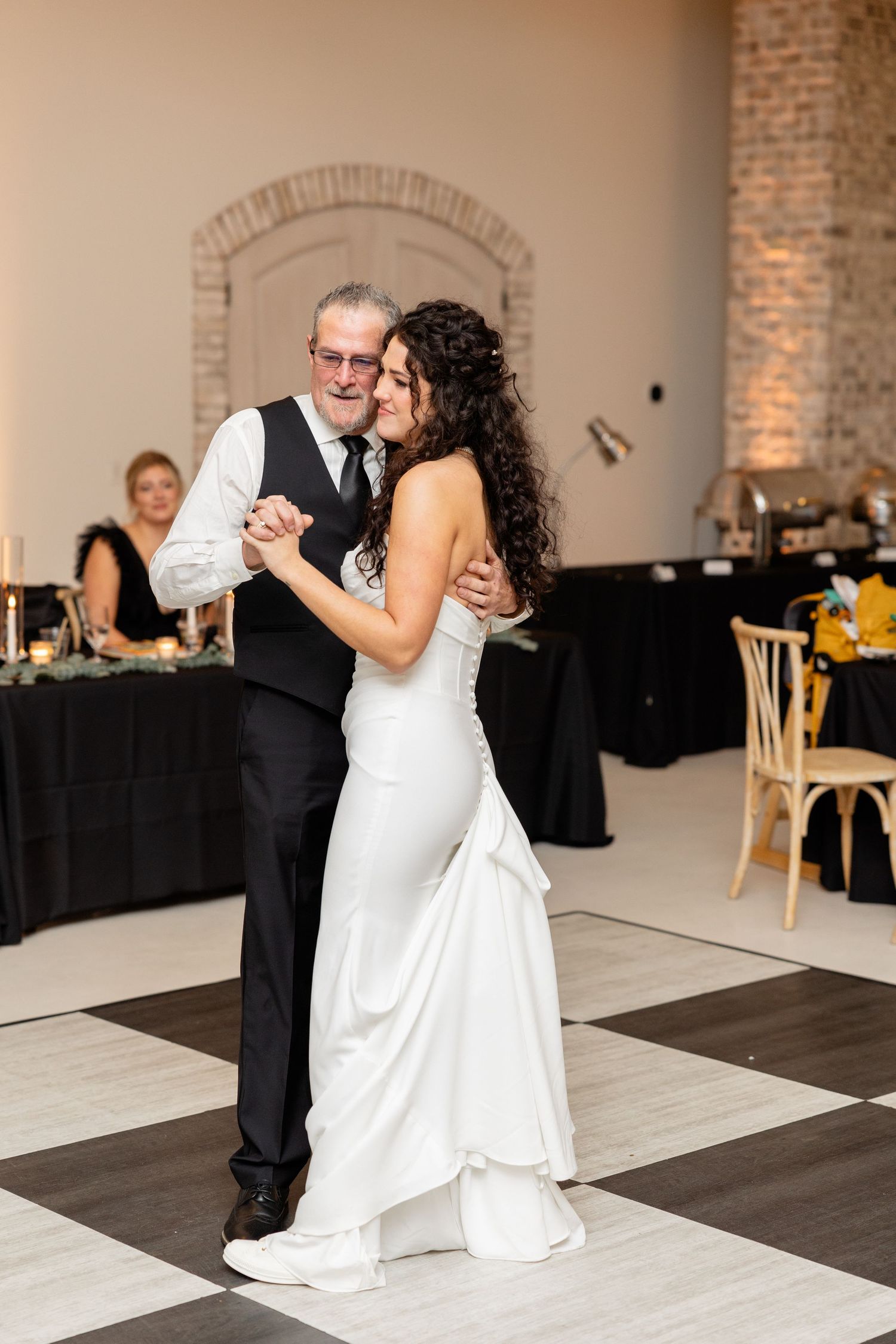 Couple sharing a romantic dance on a black and white checkered floor at their wedding reception.