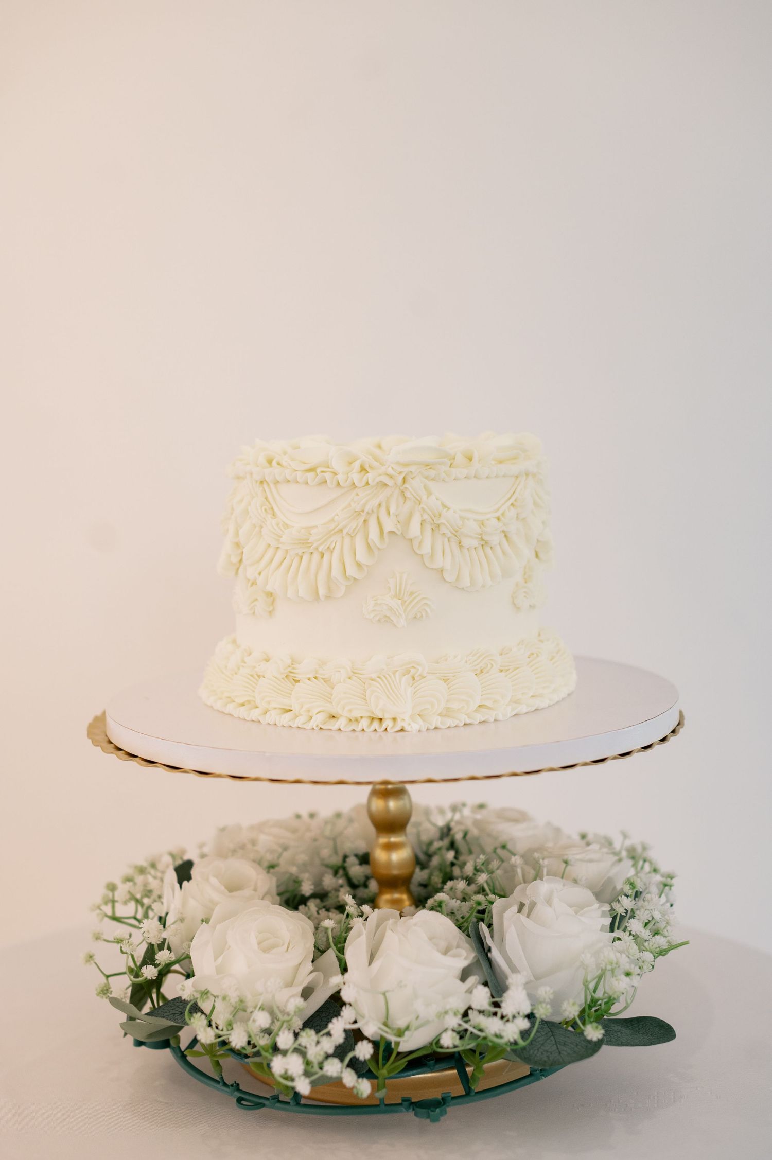 An elegant white wedding cake decorated with delicate frosting and surrounded by fresh white flowers.