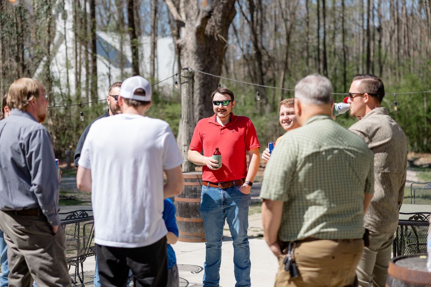 Group gathered outdoors in a wooded area during a casual daytime event.