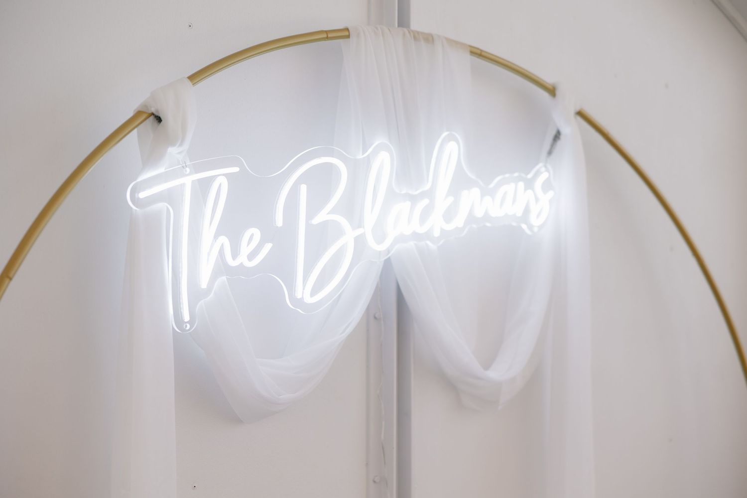 Illuminated neon sign display against a white backdrop at a wedding venue.