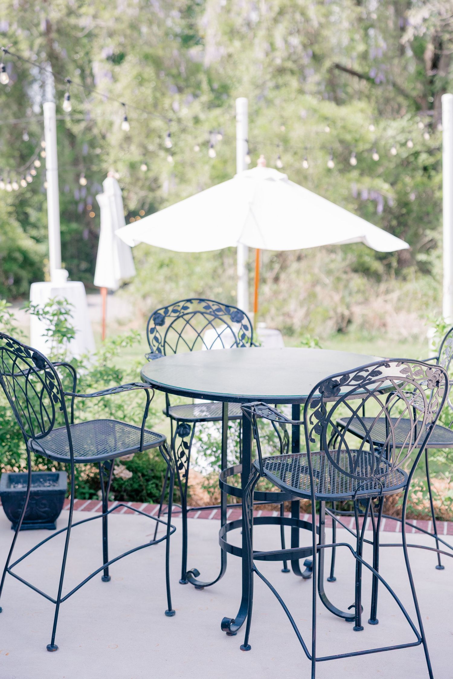 Wrought iron patio furniture with white umbrellas arranged on an outdoor dining terrace.