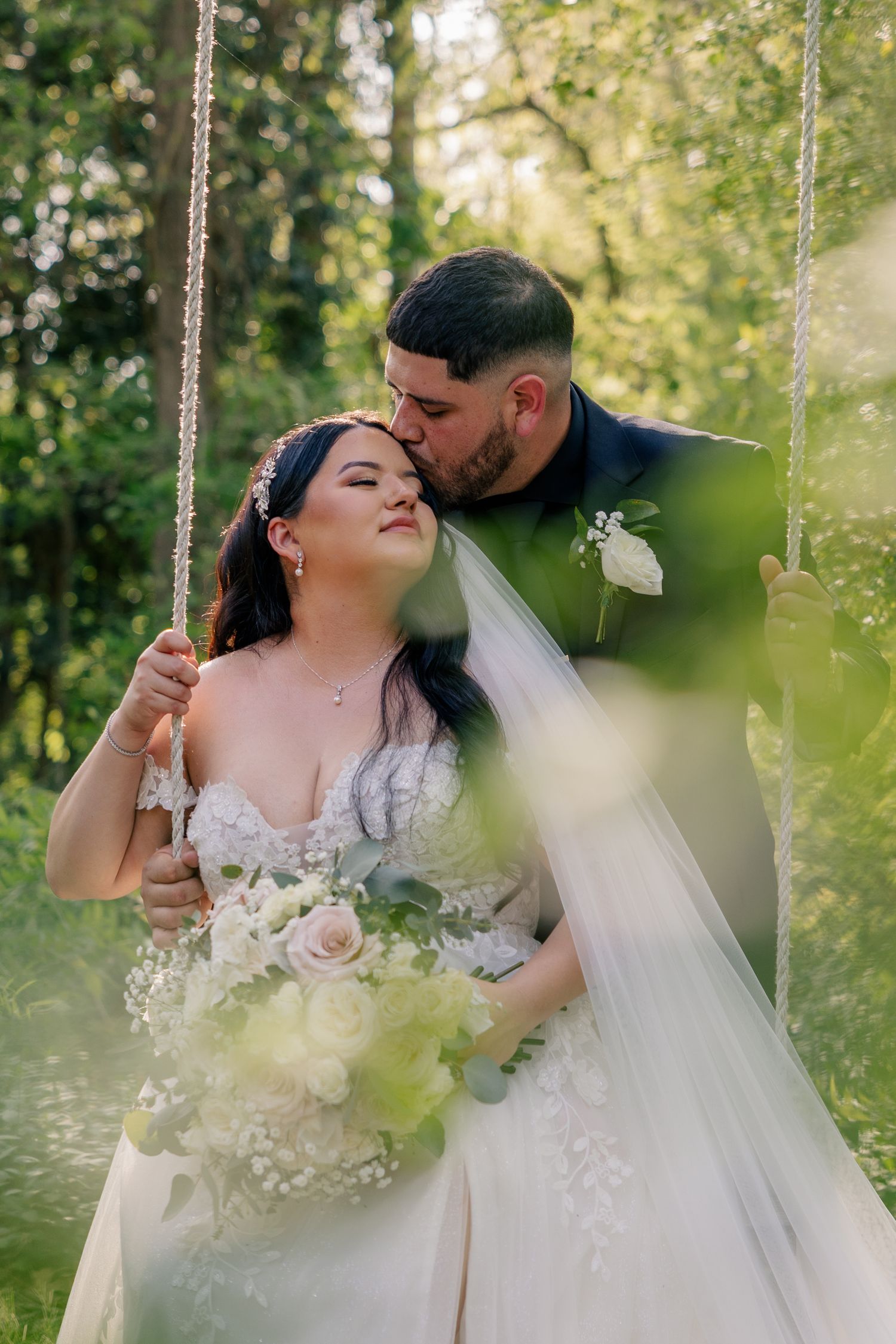 Romantic wedding photos taken in a sunlit garden with greenery showing tender moments between newlyweds.