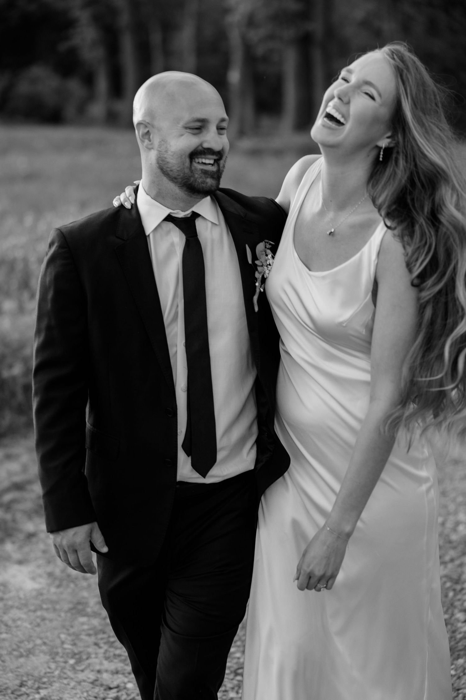 A joyful couple laughs together during their black and white outdoor photo session.