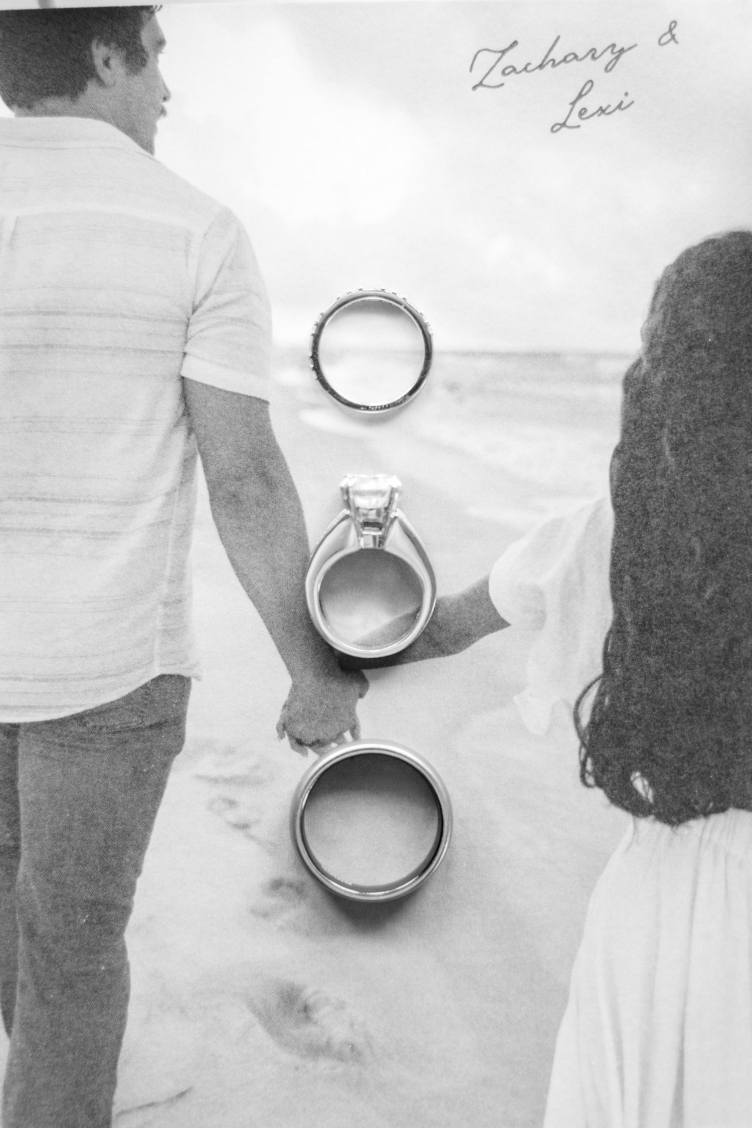 Wedding rings being held by a couple in a black and white photograph.