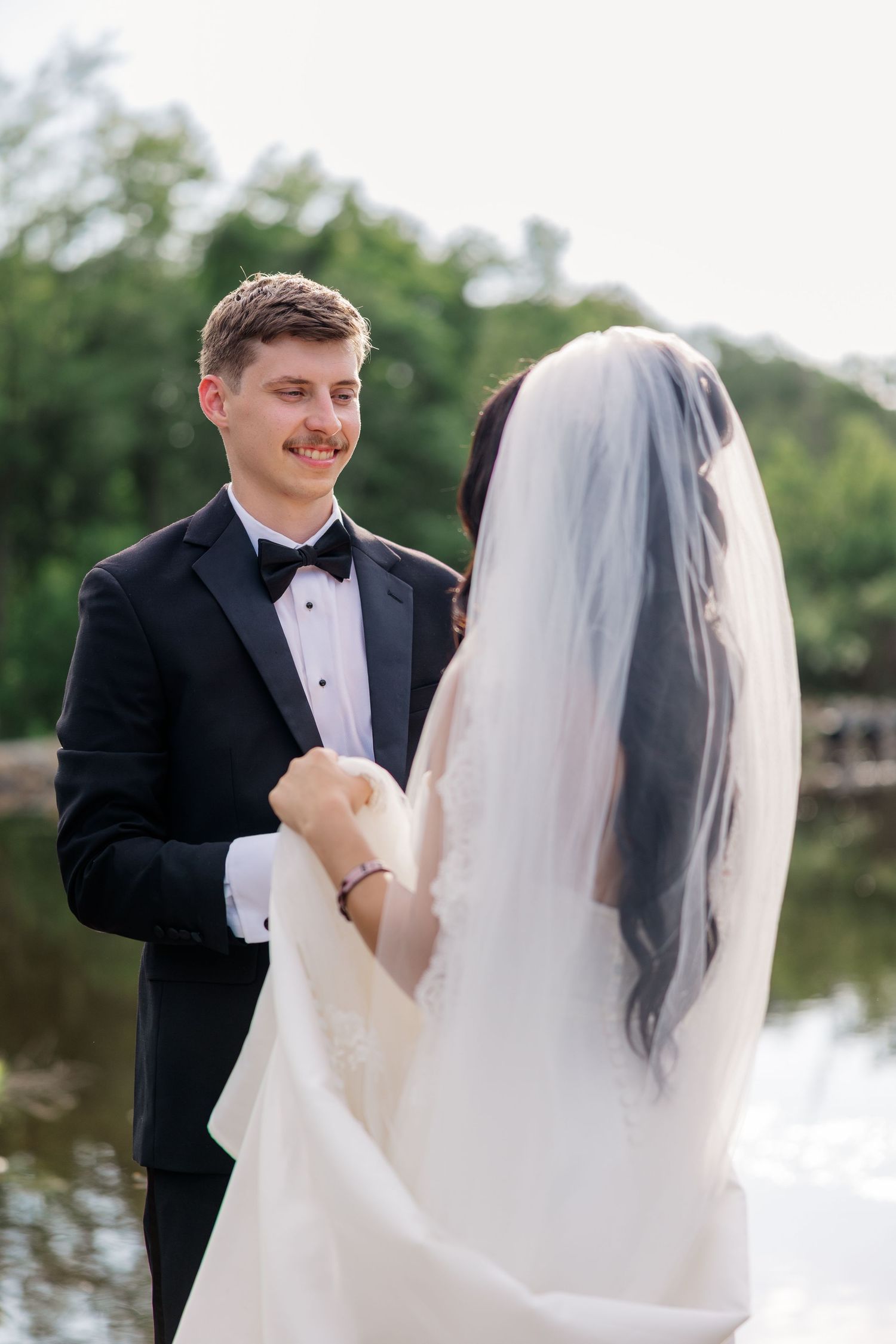 Intimate first look moment between bride and groom by a serene lake.
