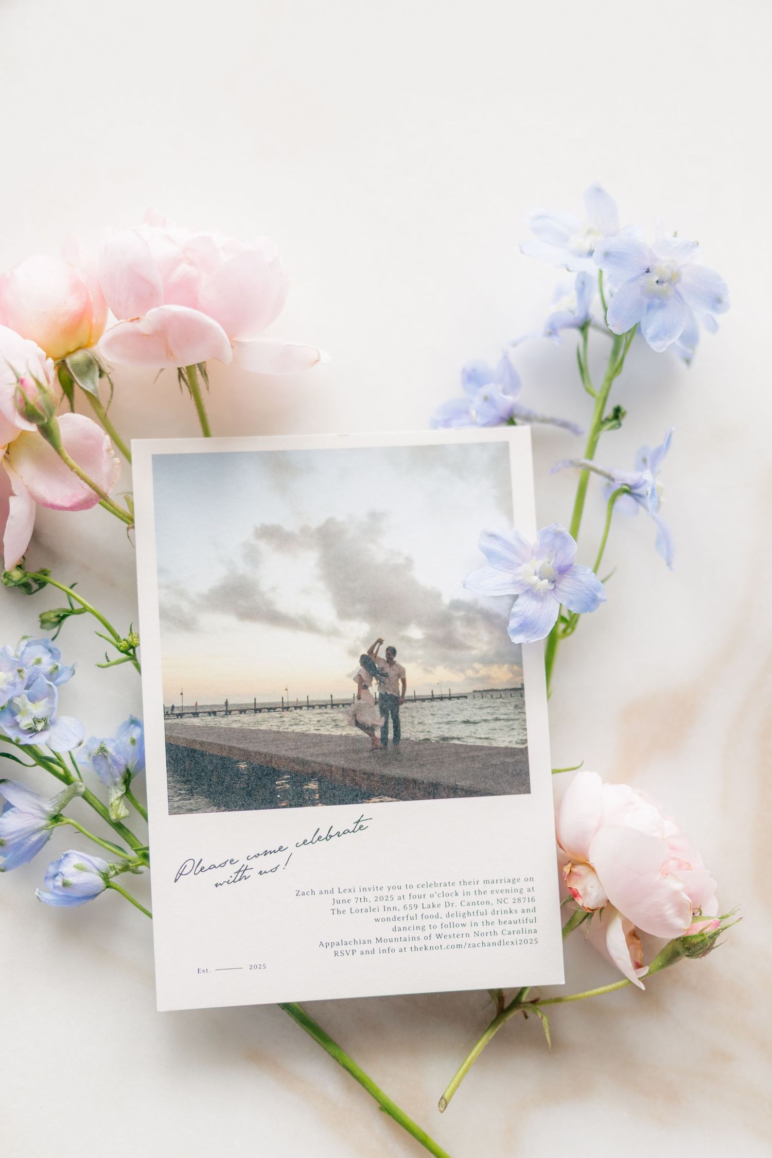 Romantic sepia-toned photographs arranged with delicate pink roses and blue forget-me-not flowers on a white surface.