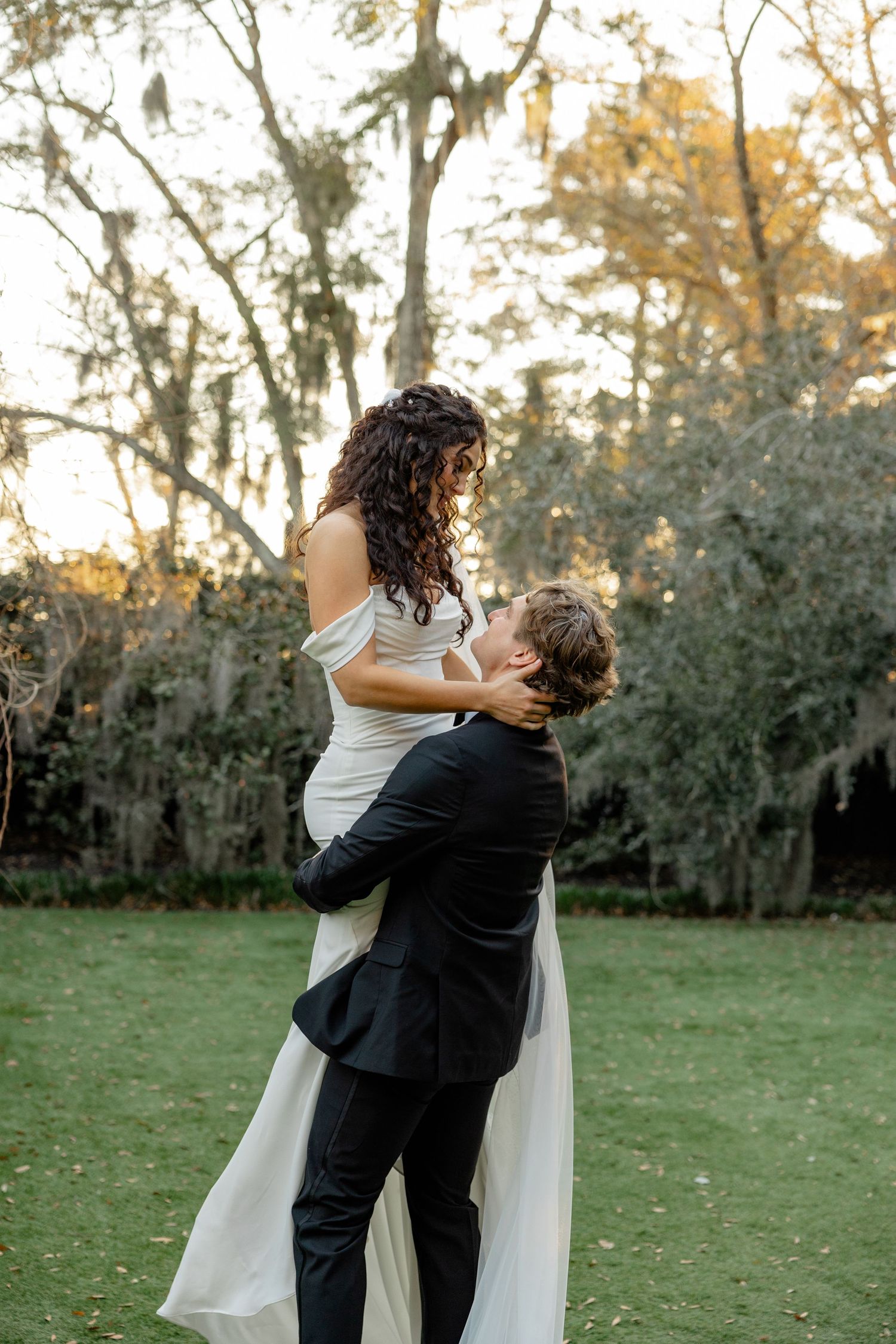 A romantic moment captured in a garden setting with Spanish moss hanging from trees.