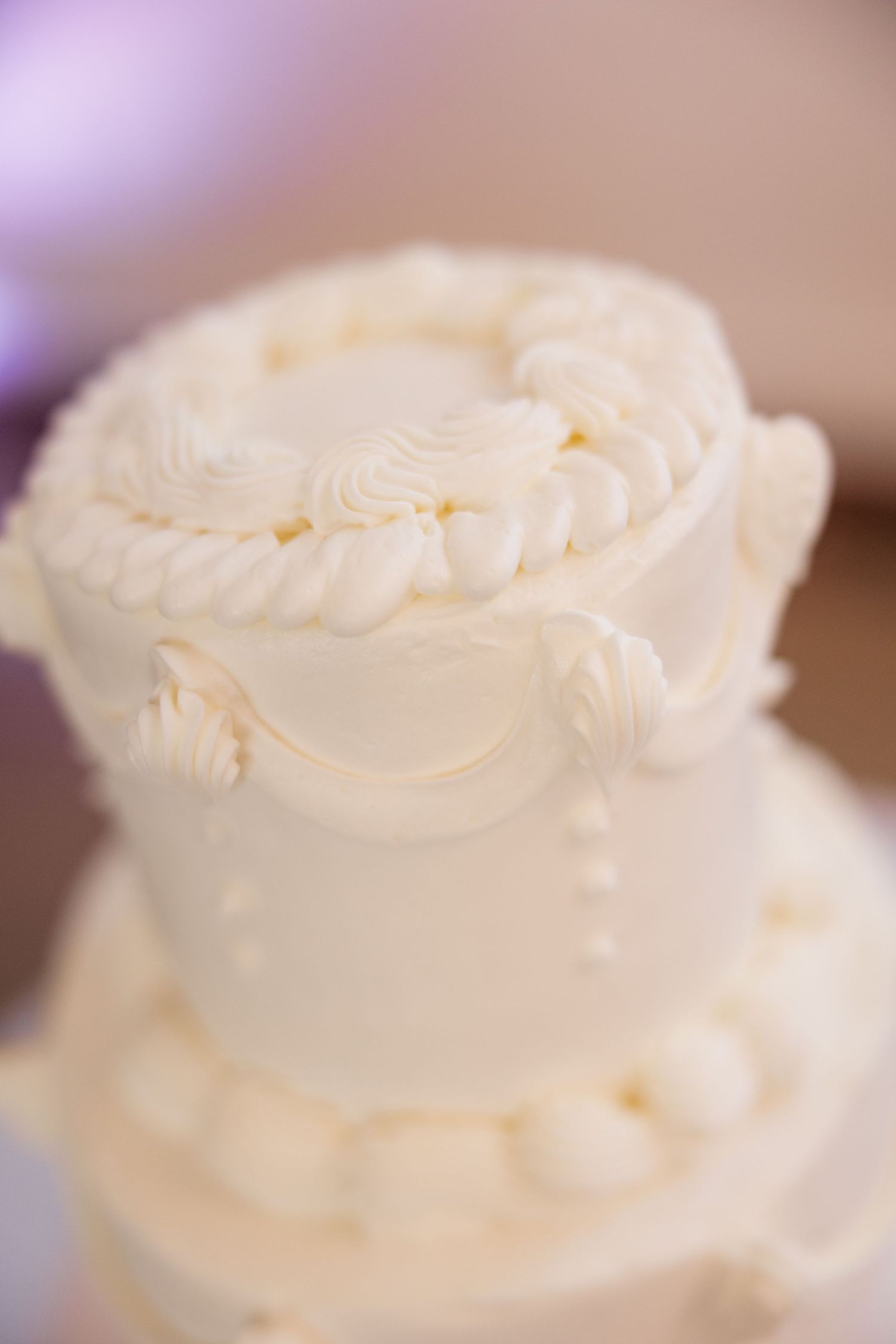 Close-up detail shot of a white wedding cake with delicate piped frosting design.