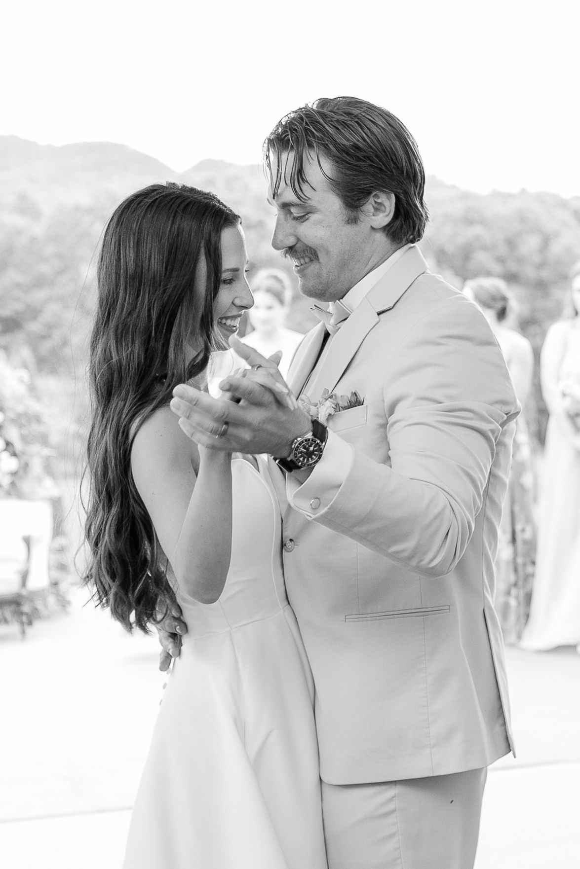 A couple shares their first dance together at their wedding reception in white attire.