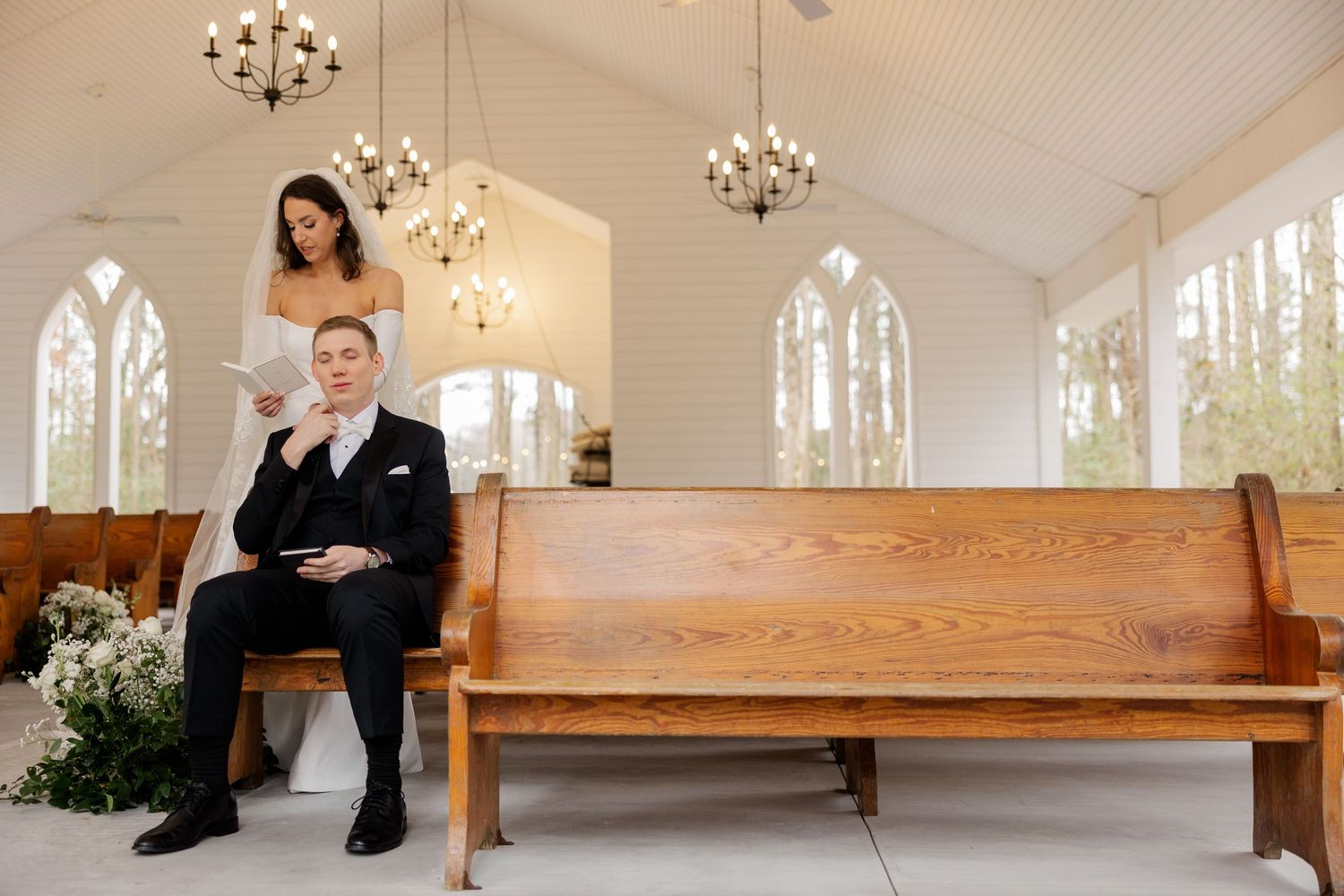 Interior of a modern chapel with decorative chandeliers and wooden pews.