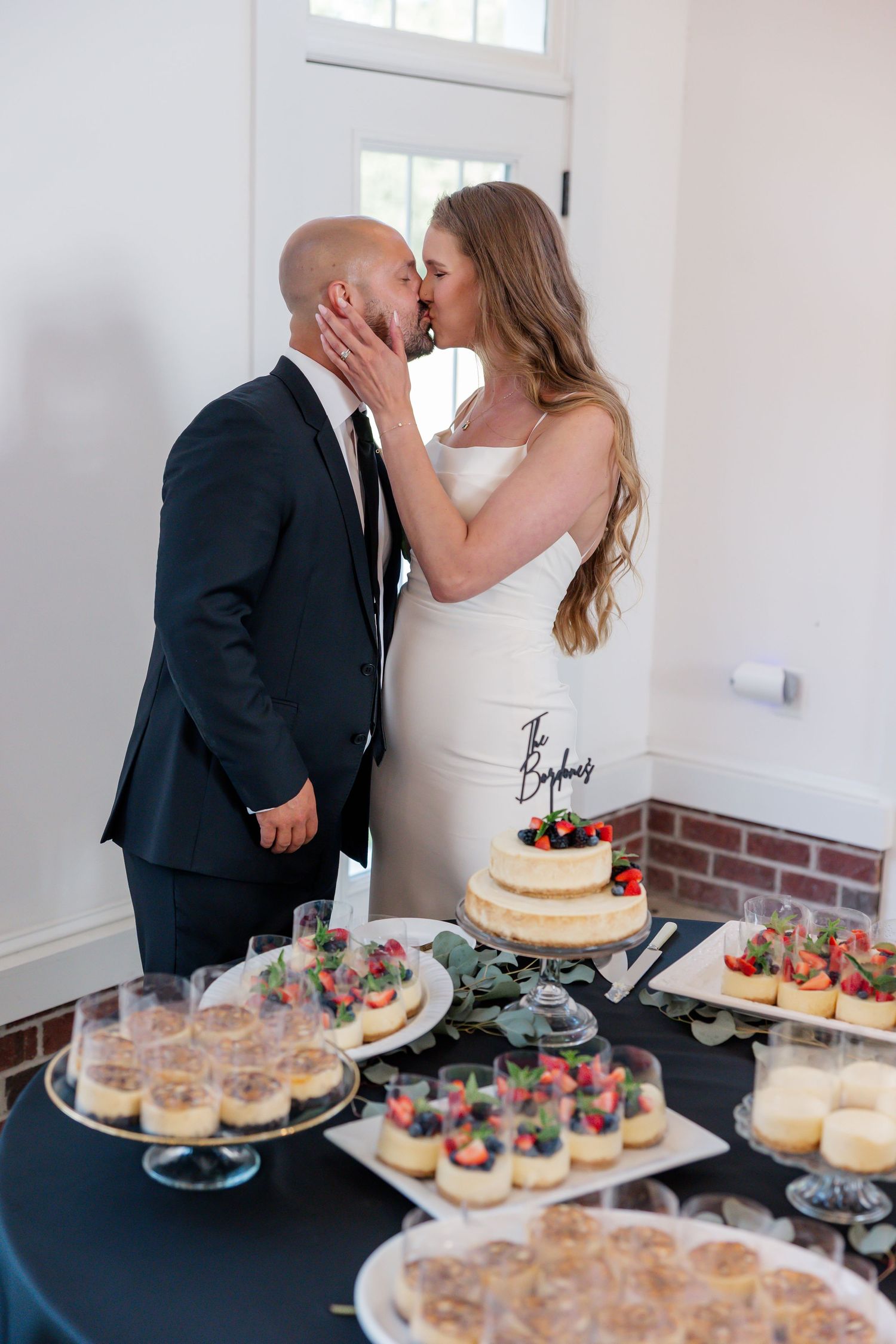 Wedding dessert table with cake and various sweets on white tablecloth.