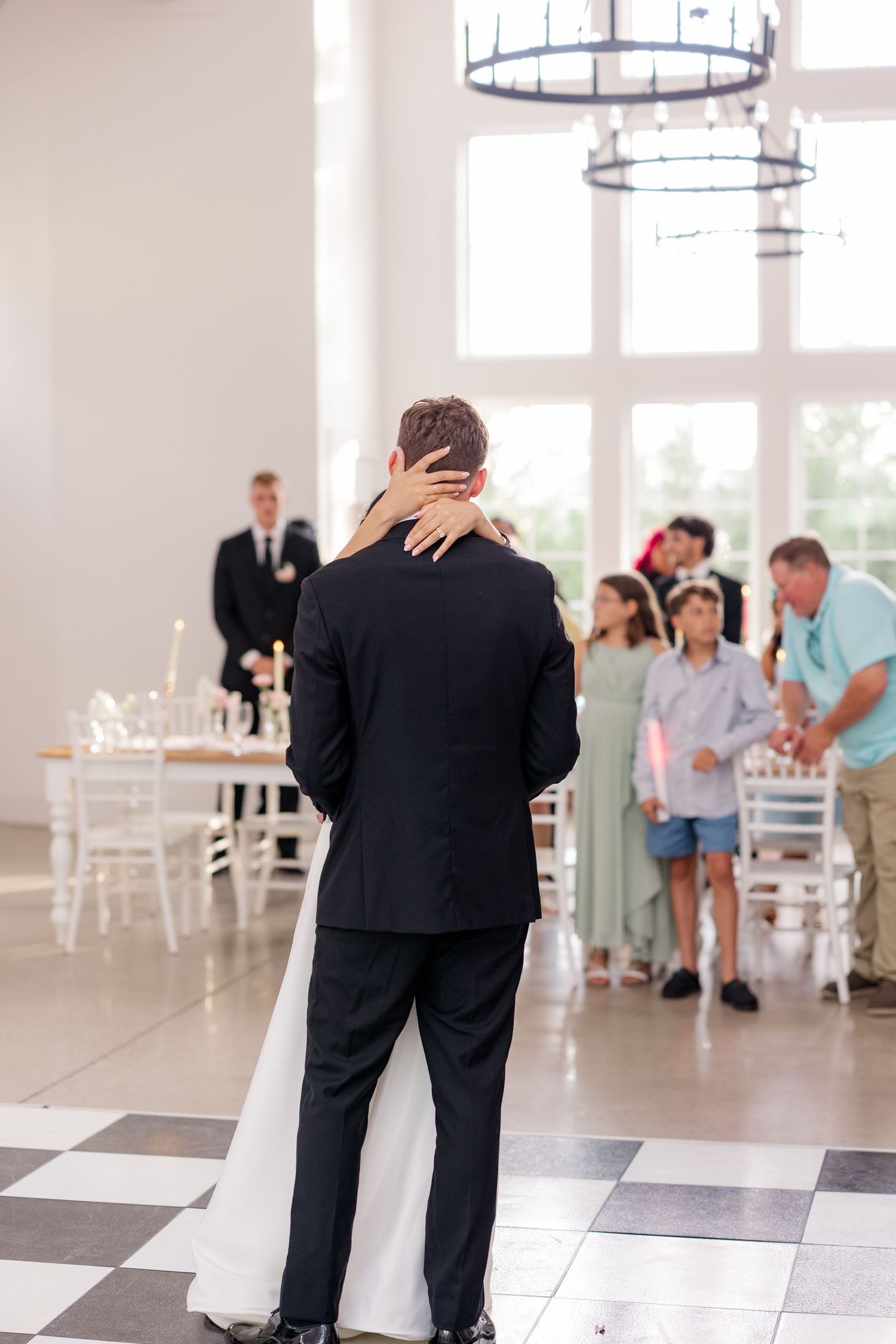 Black and white checkered dance floor at an elegant indoor wedding reception venue with natural lighting.