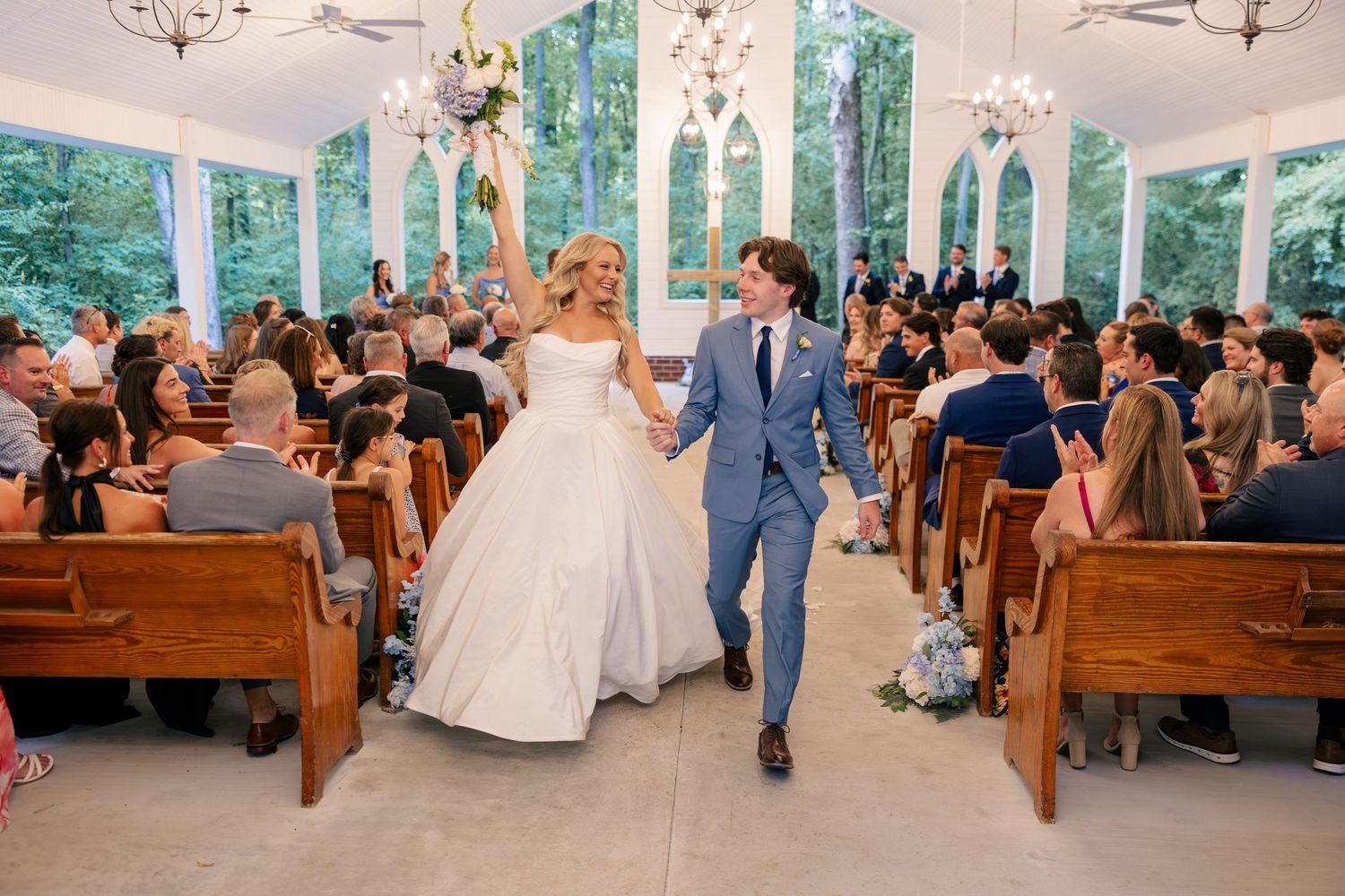 Newlyweds celebrate walking down the aisle in a beautiful chapel wedding ceremony.