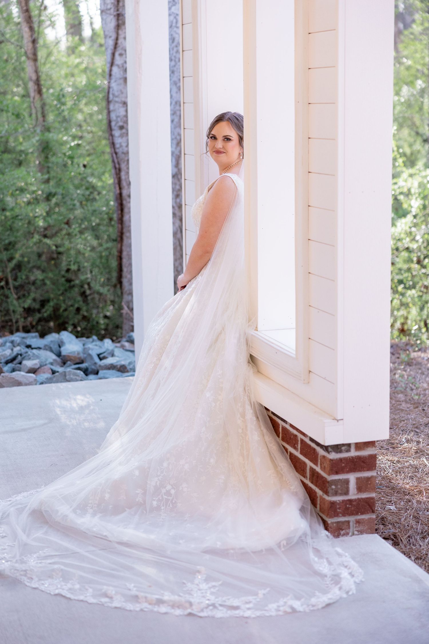 A bridal portrait showcasing an elegant lace wedding gown with a cathedral-length train.