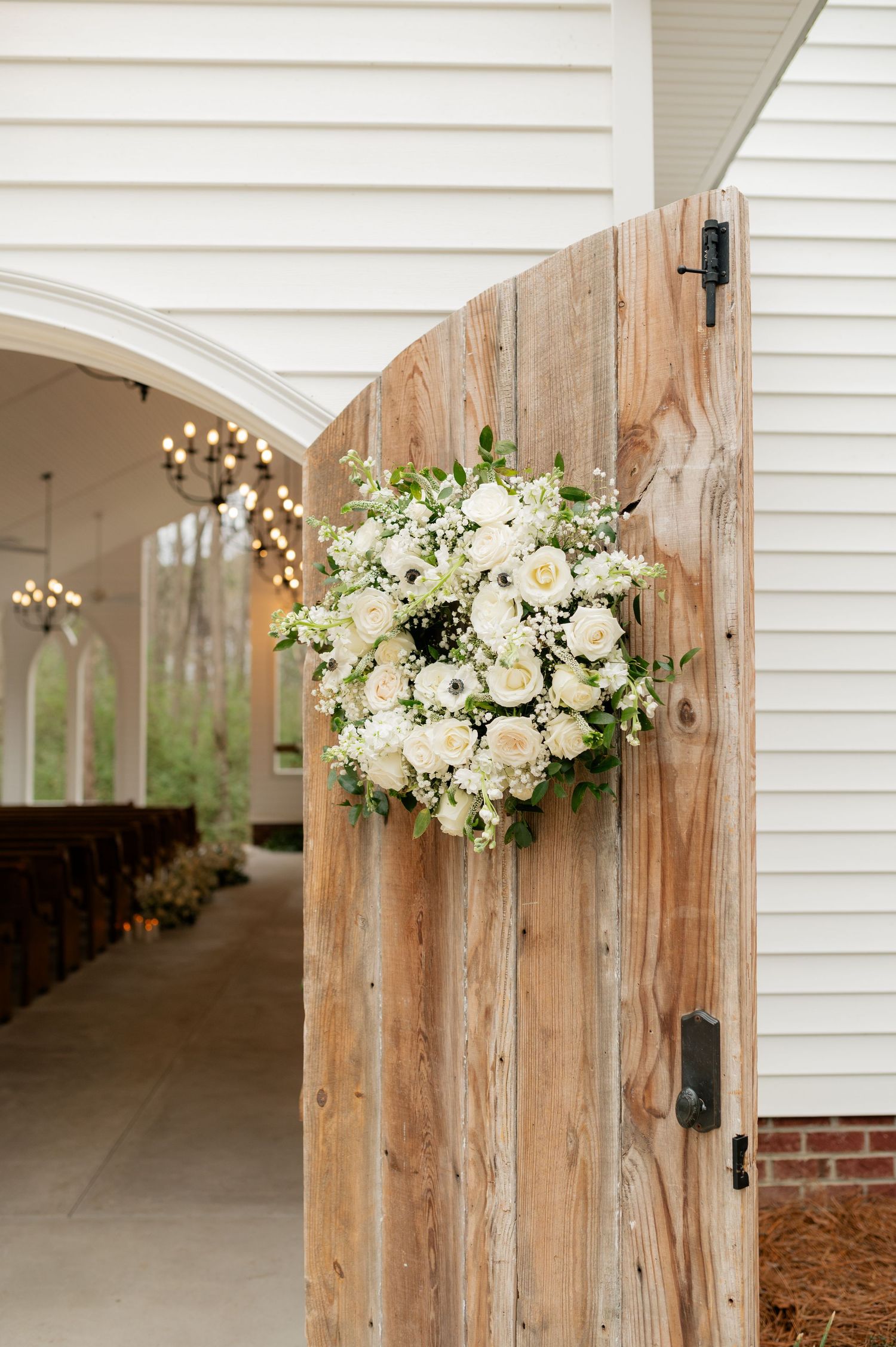 A rustic wooden church door adorned with an elegant white floral arrangement.