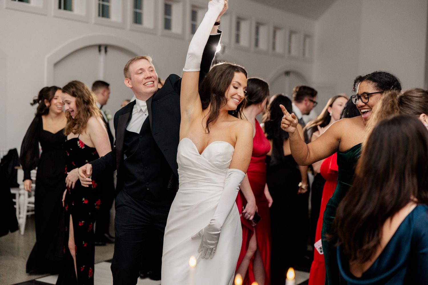 Wedding guests celebrate with joy and energy while dancing together on a crowded dance floor.