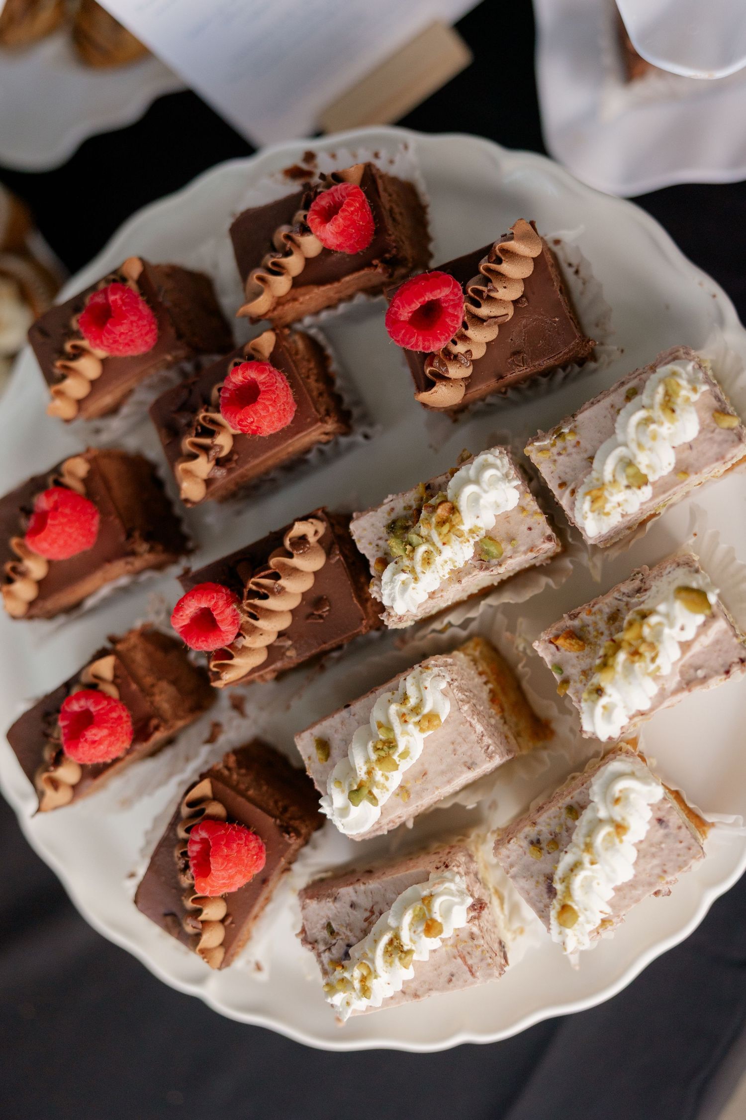 Elegant dessert plate featuring chocolate and vanilla pastries topped with fresh raspberries and whipped cream.