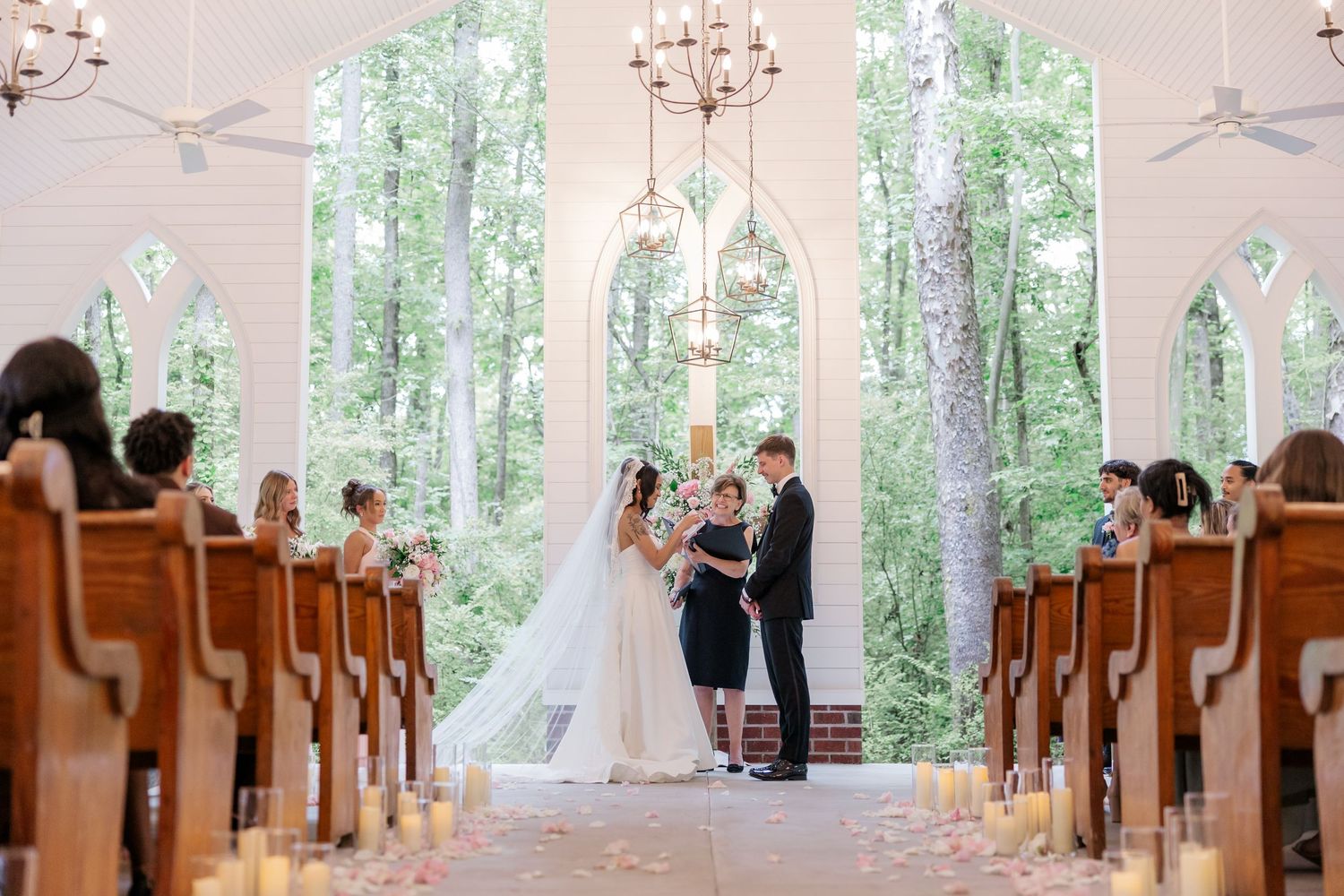 Chapel interior decorated for a wedding with wooden pews and natural light streaming through windows.