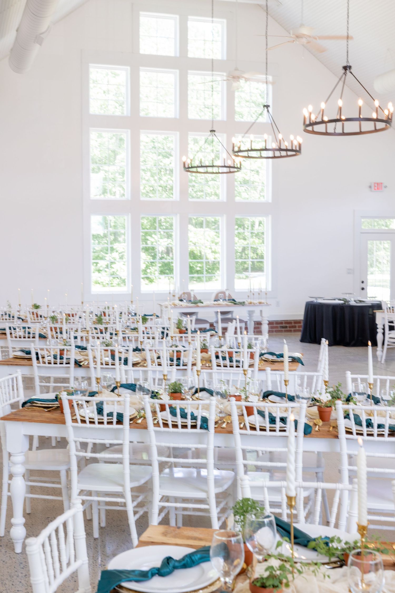 Elegant white reception hall with chandelier lighting and white chiavari chairs.