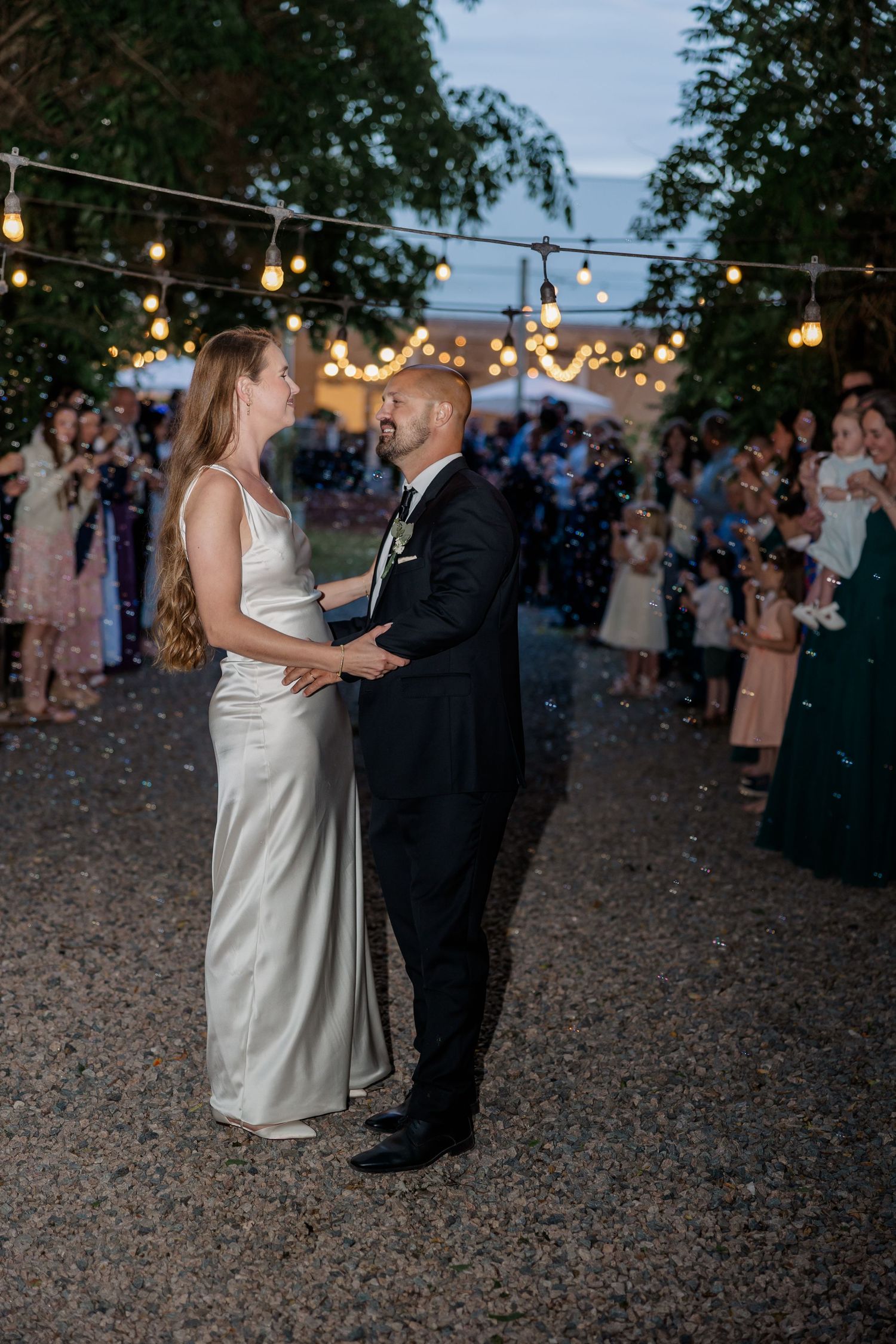 Evening dance under string lights at outdoor wedding reception.