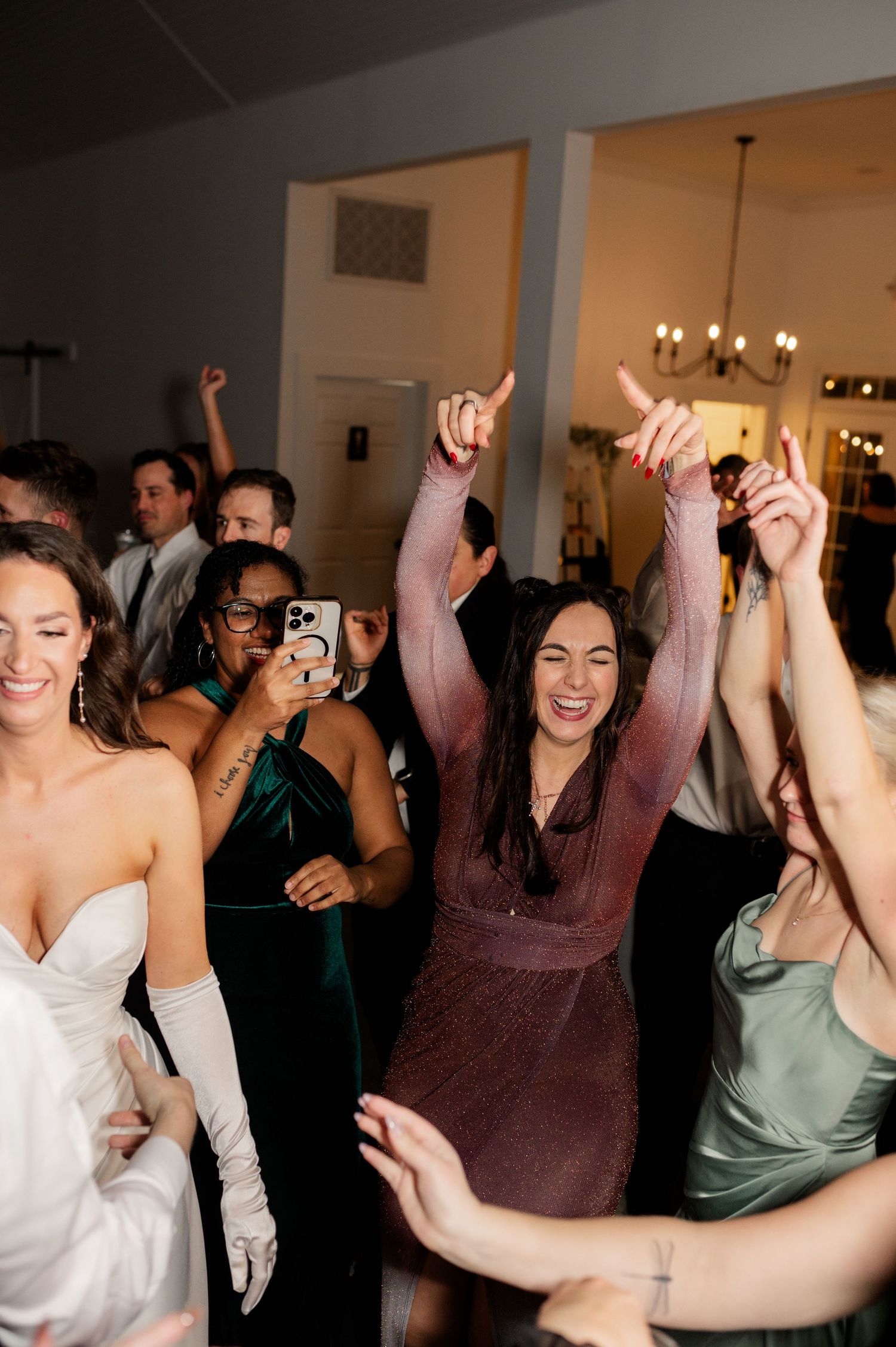 Wedding reception dance party with guests celebrating enthusiastically on the dance floor.