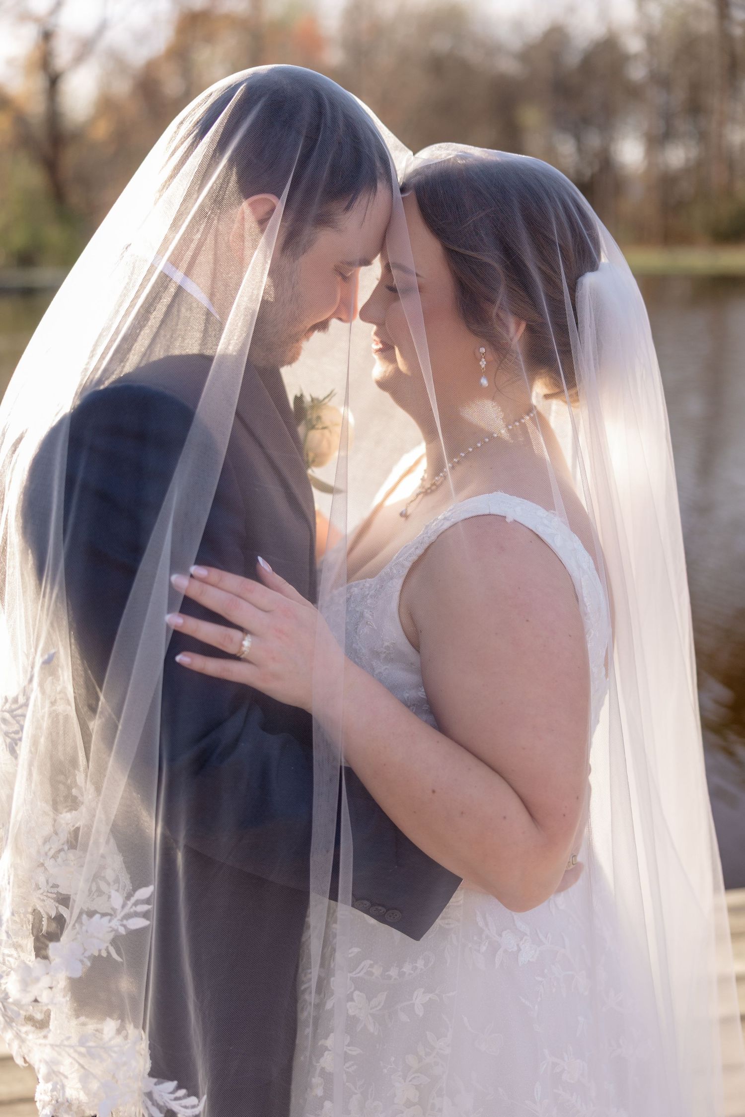 Romantic wedding moment captured through a flowing white veil against a natural backdrop.