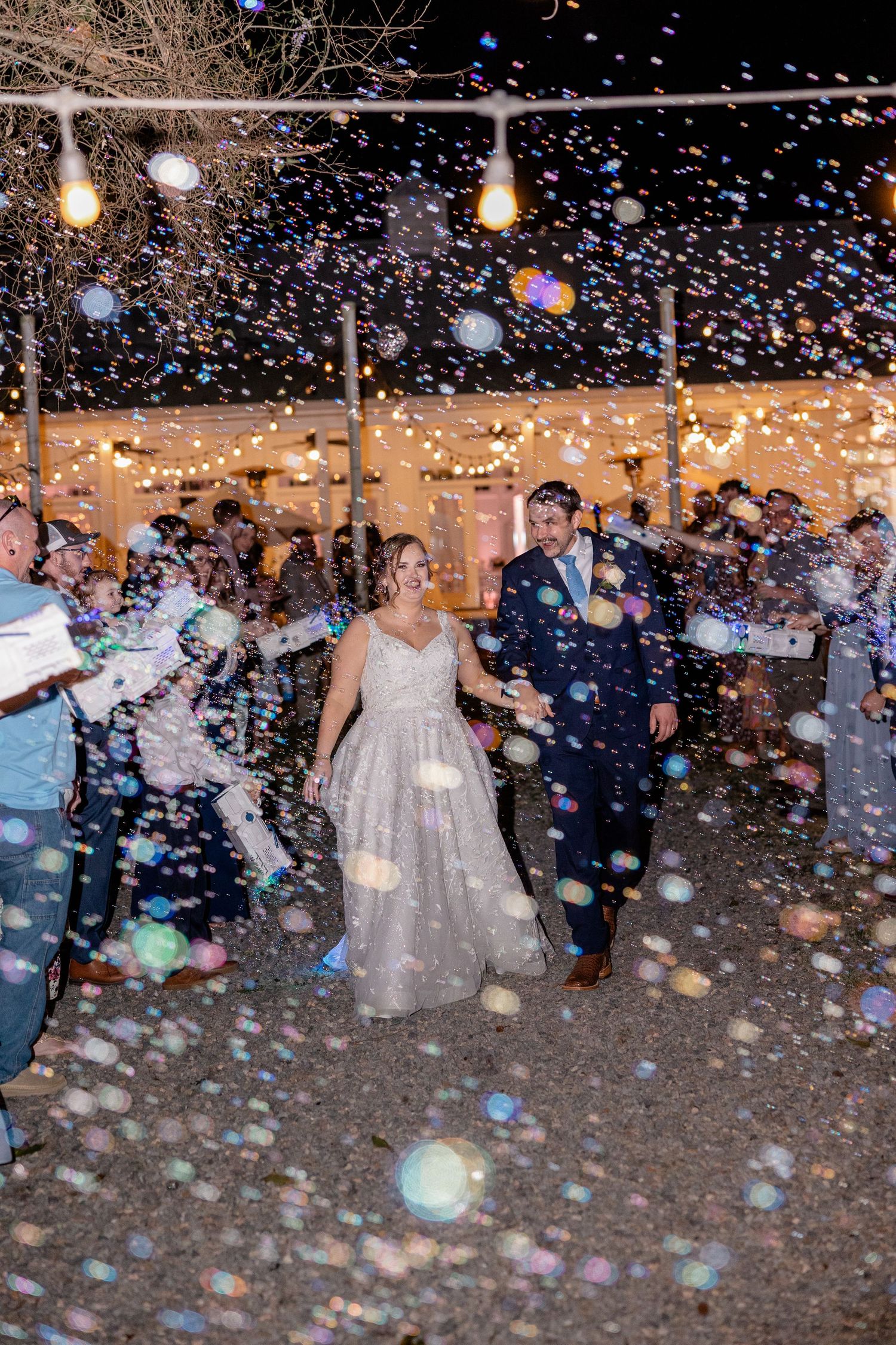 Wedding celebration exit with bubbles and confetti creating a magical nighttime atmosphere.