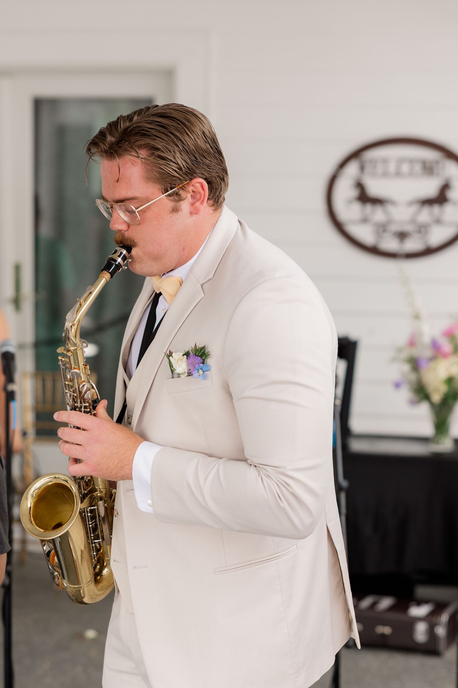 A musician in a white suit jacket plays the saxophone during a wedding celebration.