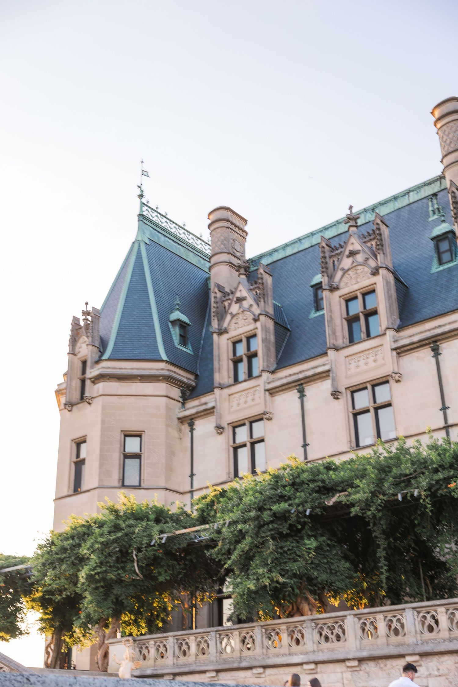 Exterior view of a grand historic mansion with Gothic architecture and blue slate roof.