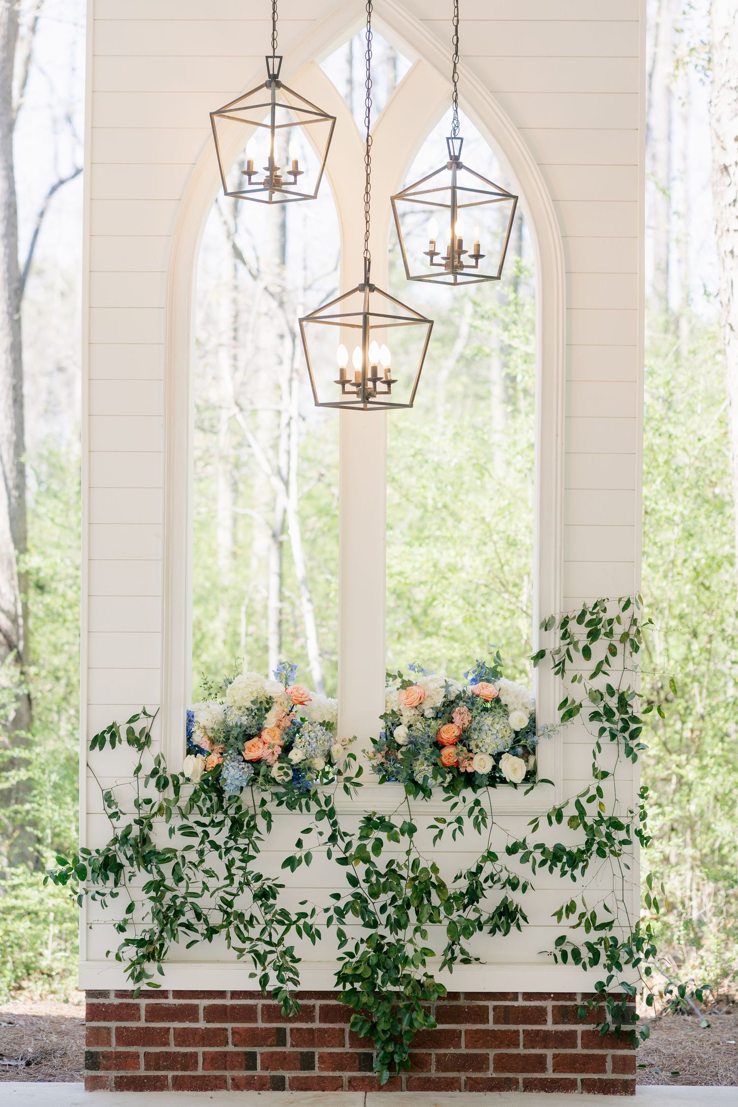 Elegant lantern lights and floral garlands decorating a white-pillared wedding venue entrance.